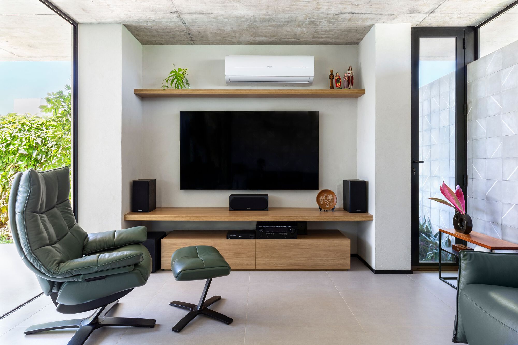 Media niche with timber shelving flanked by full-height glazing opening to planted courtyard