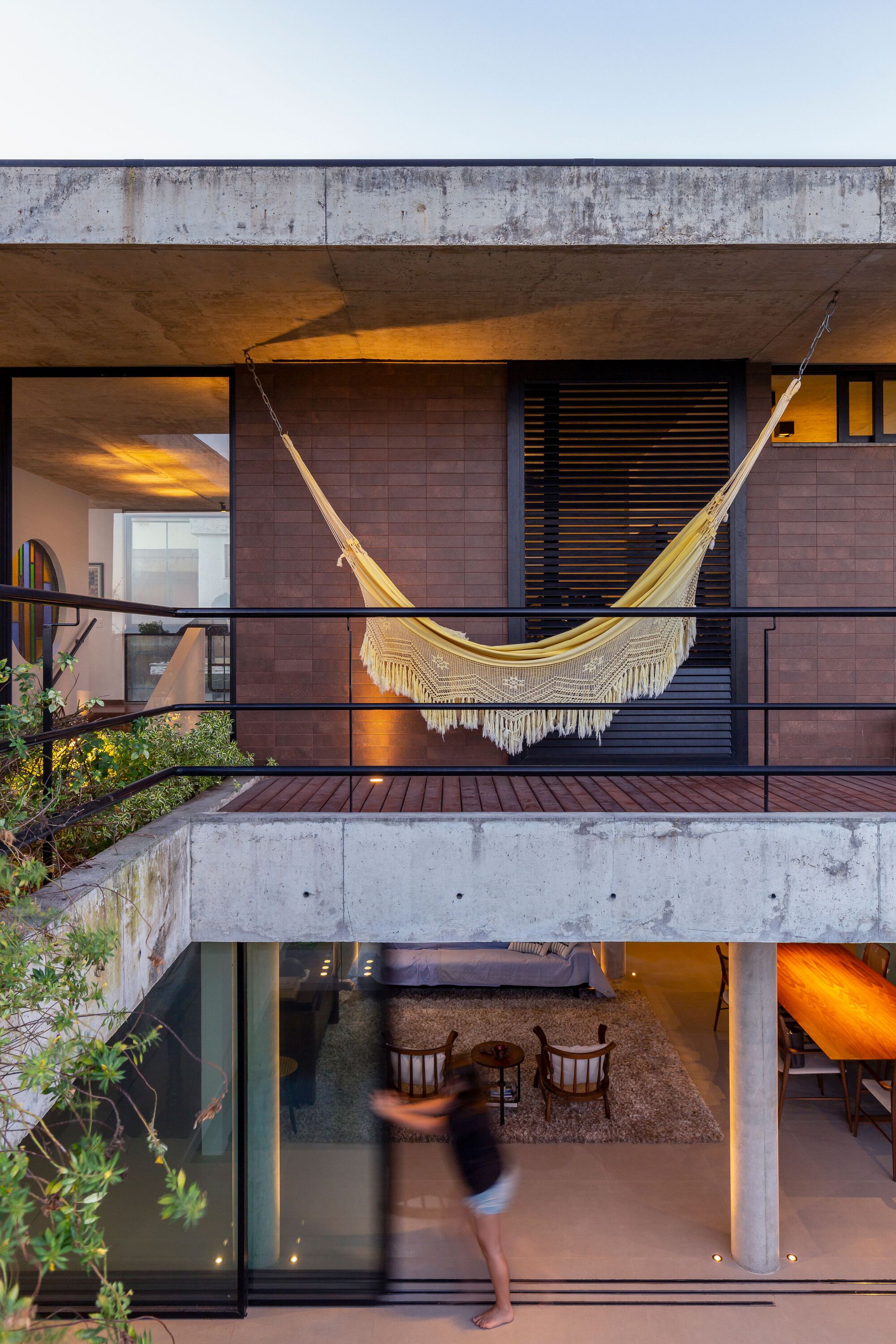 Stacked terraces with concrete slabs and a hammock overlooking an interior space at dusk