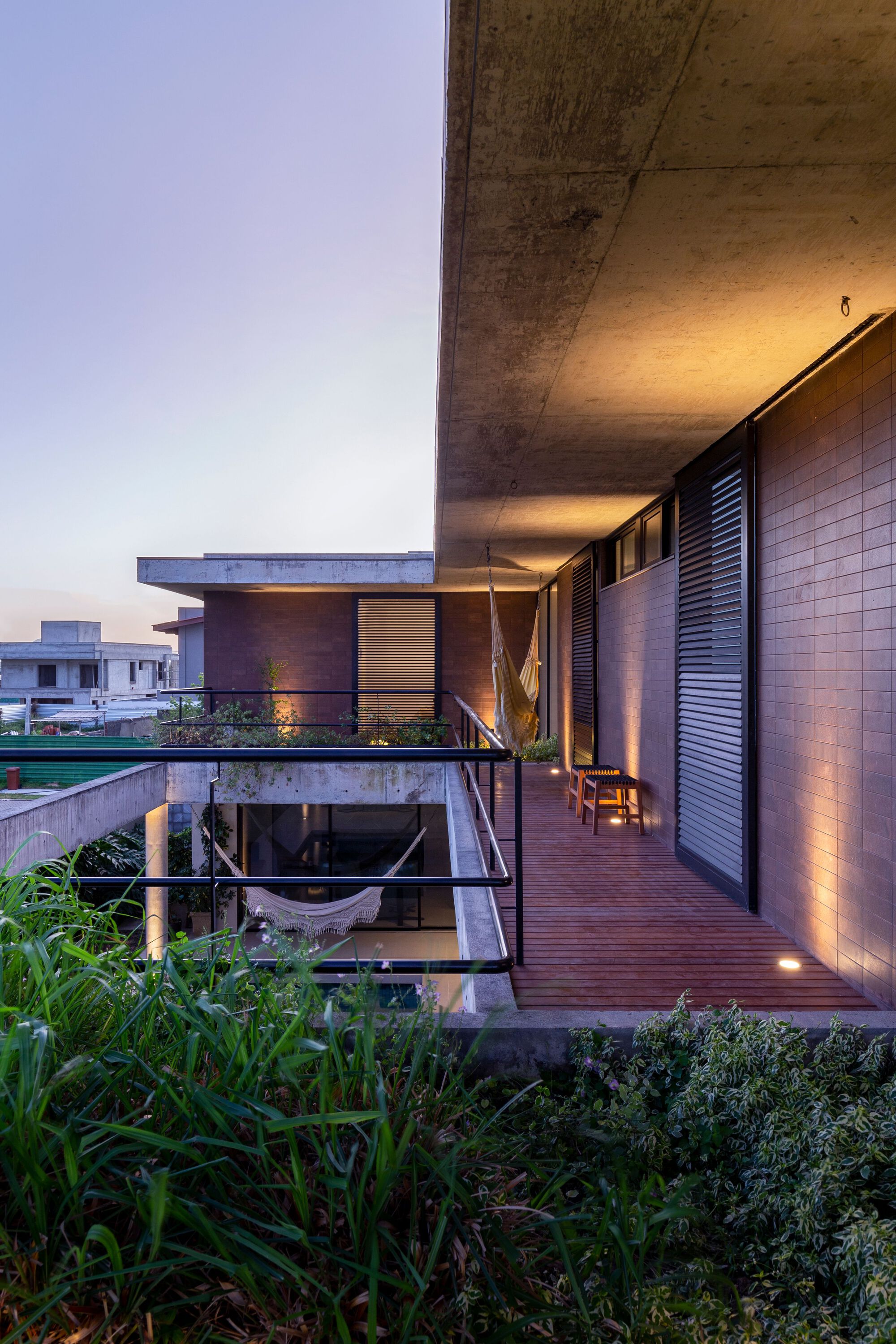 Timber deck terrace beneath a deep concrete soffit with uplighting at twilight