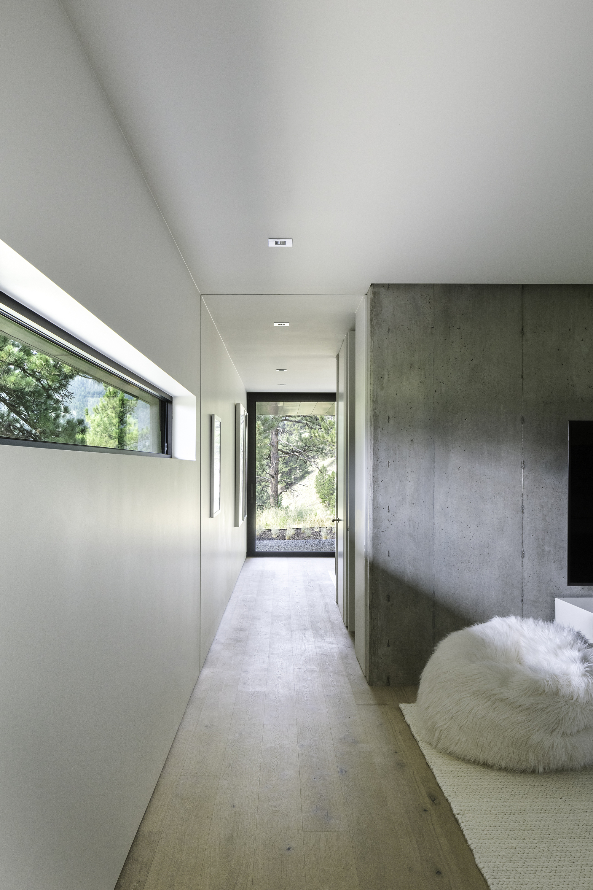 Corridor with board-formed concrete wall and high clerestory glazing leading to an exterior door