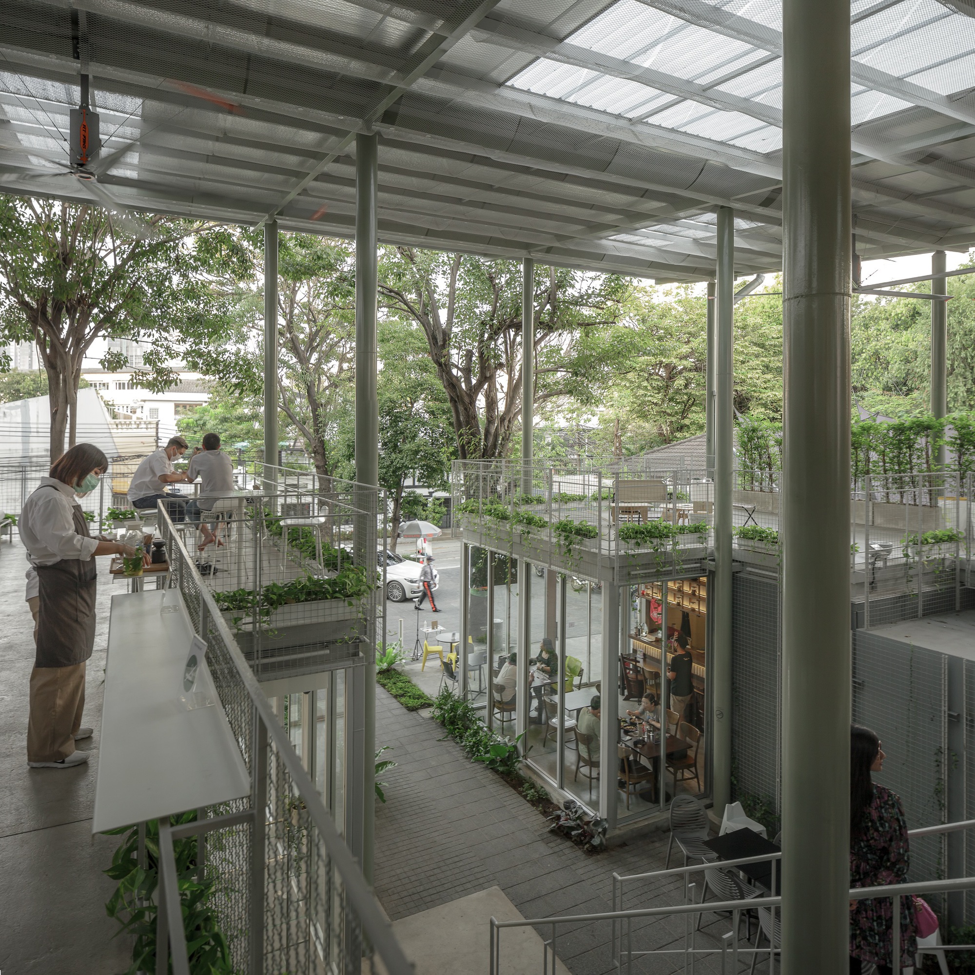 Upper-level walkway overlooking the multi-story atrium with mesh balustrades and trees growing through the space