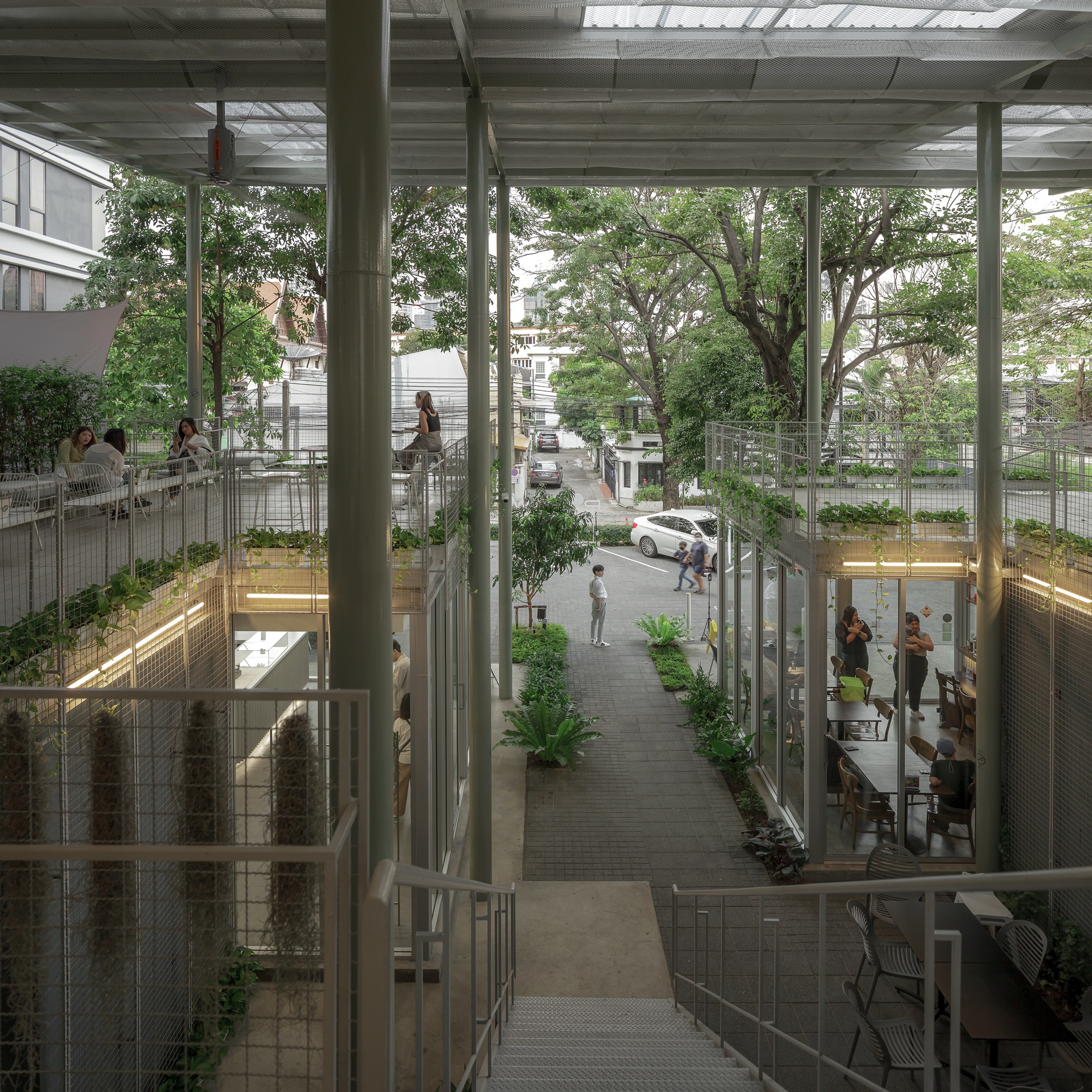 View down into the central courtyard showing circulation paths, planted beds and people gathering below