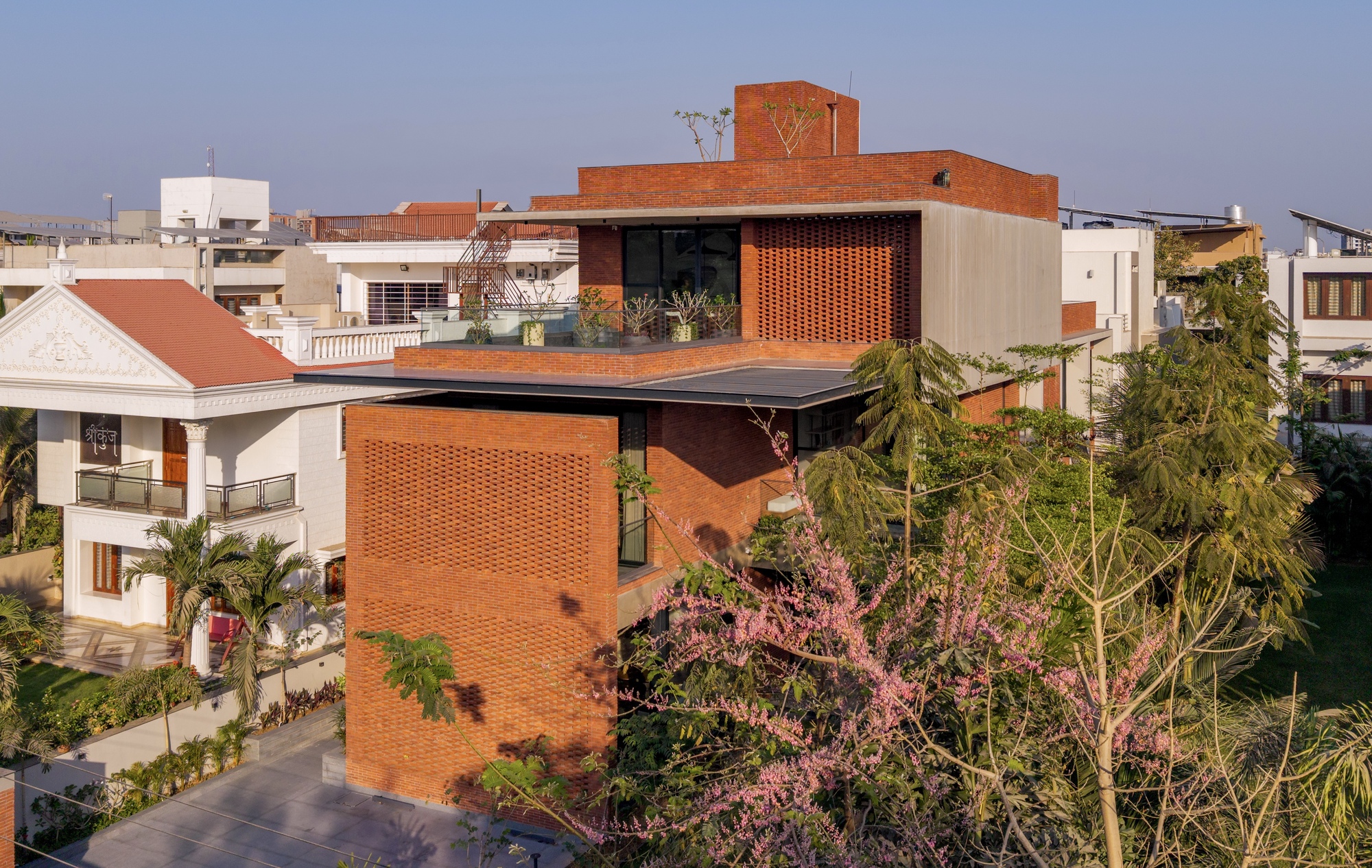 Stacked brick volumes with patterned screens and cantilevered roof plane surrounded by flowering trees