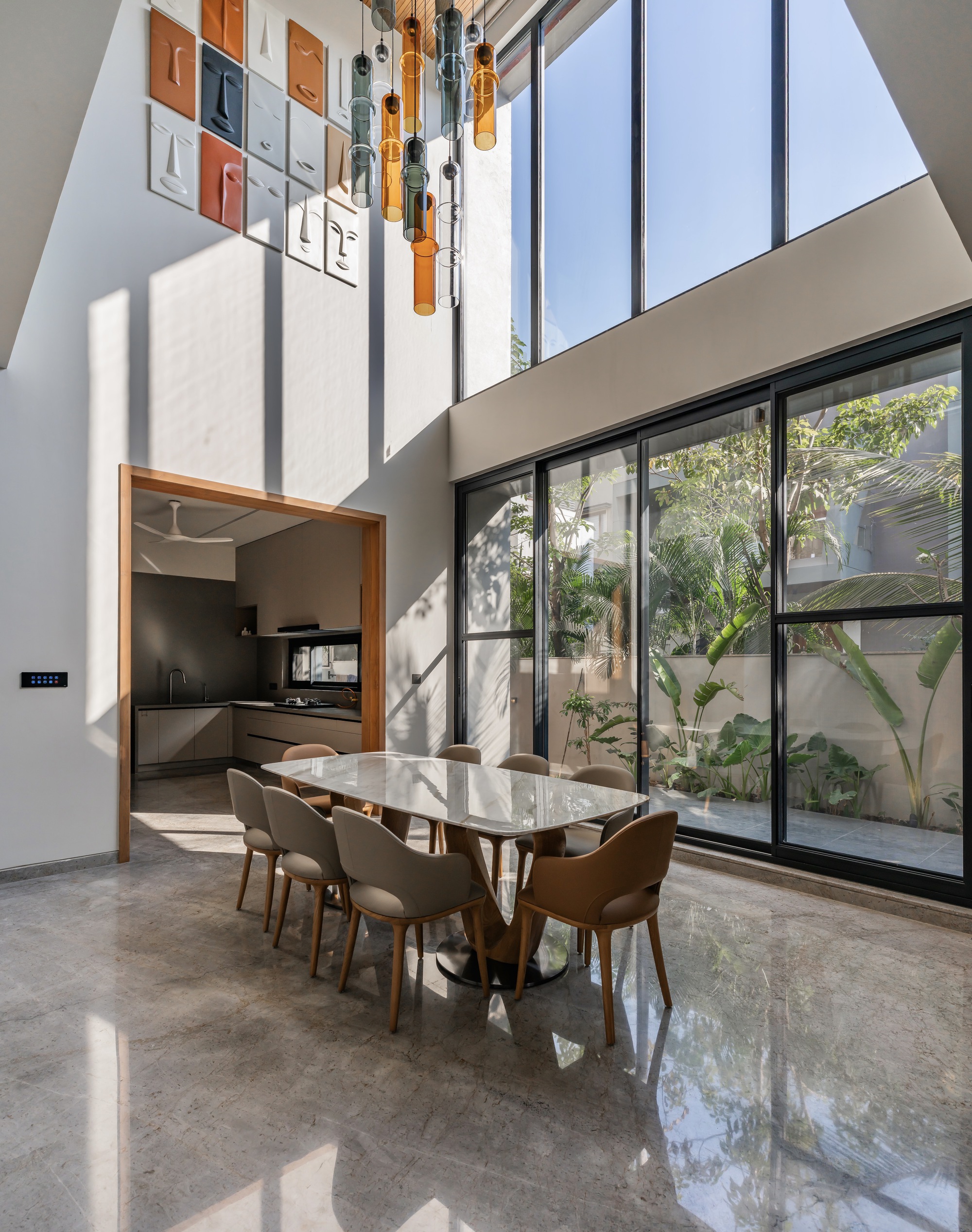 Double-height dining area with pendant lights and full-height glazing flooding polished floors with sunlight