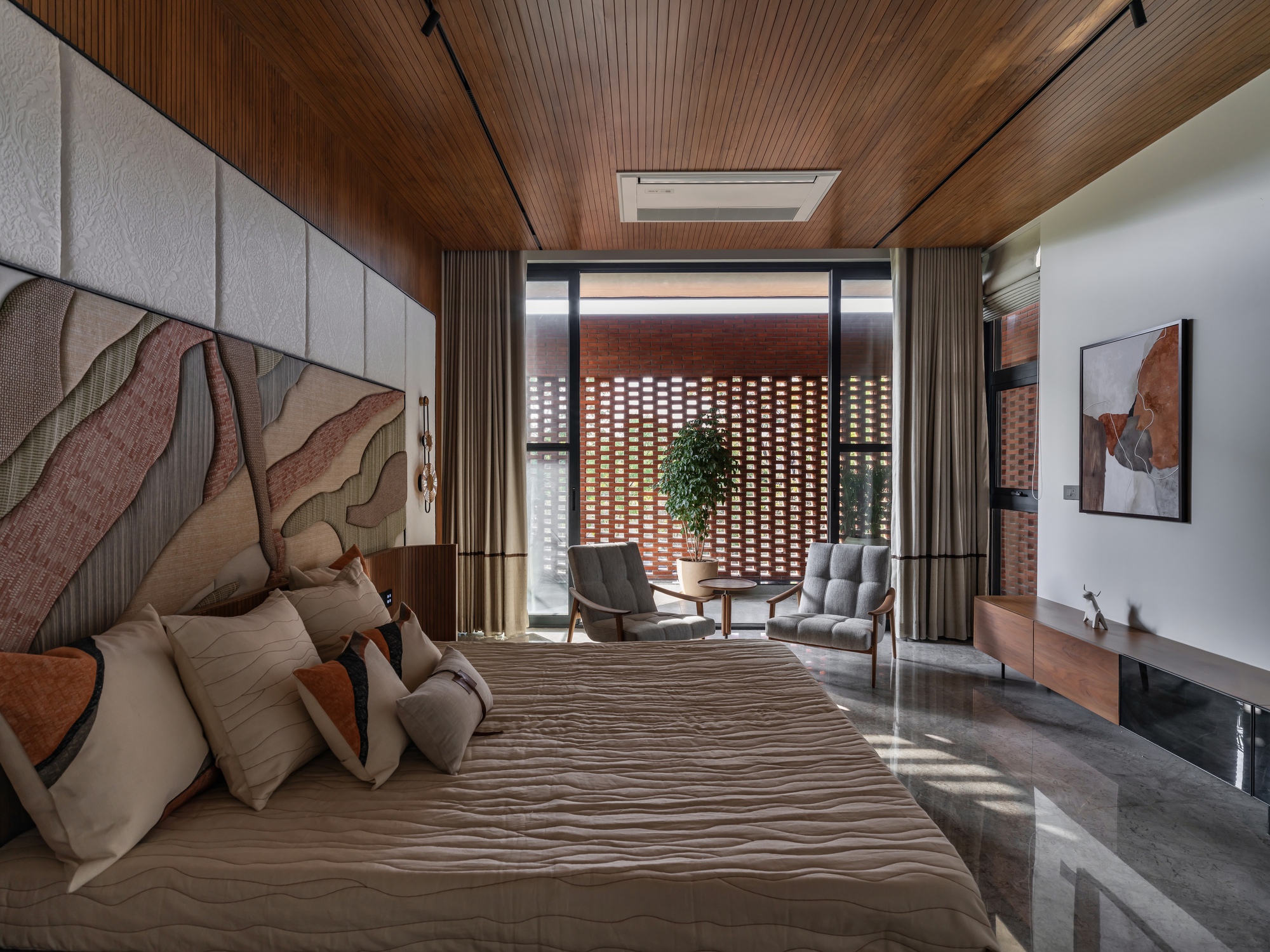 Bedroom with timber slatted ceiling looking through glazed doors toward a perforated brick screen in daylight