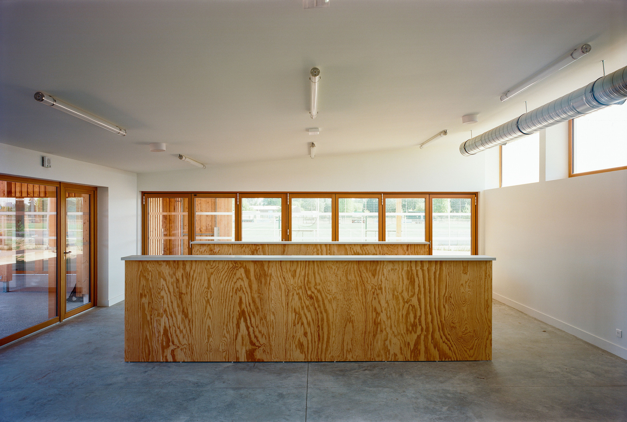 Reception area with plywood-clad counter, continuous clerestory windows, and exposed mechanical ductwork
