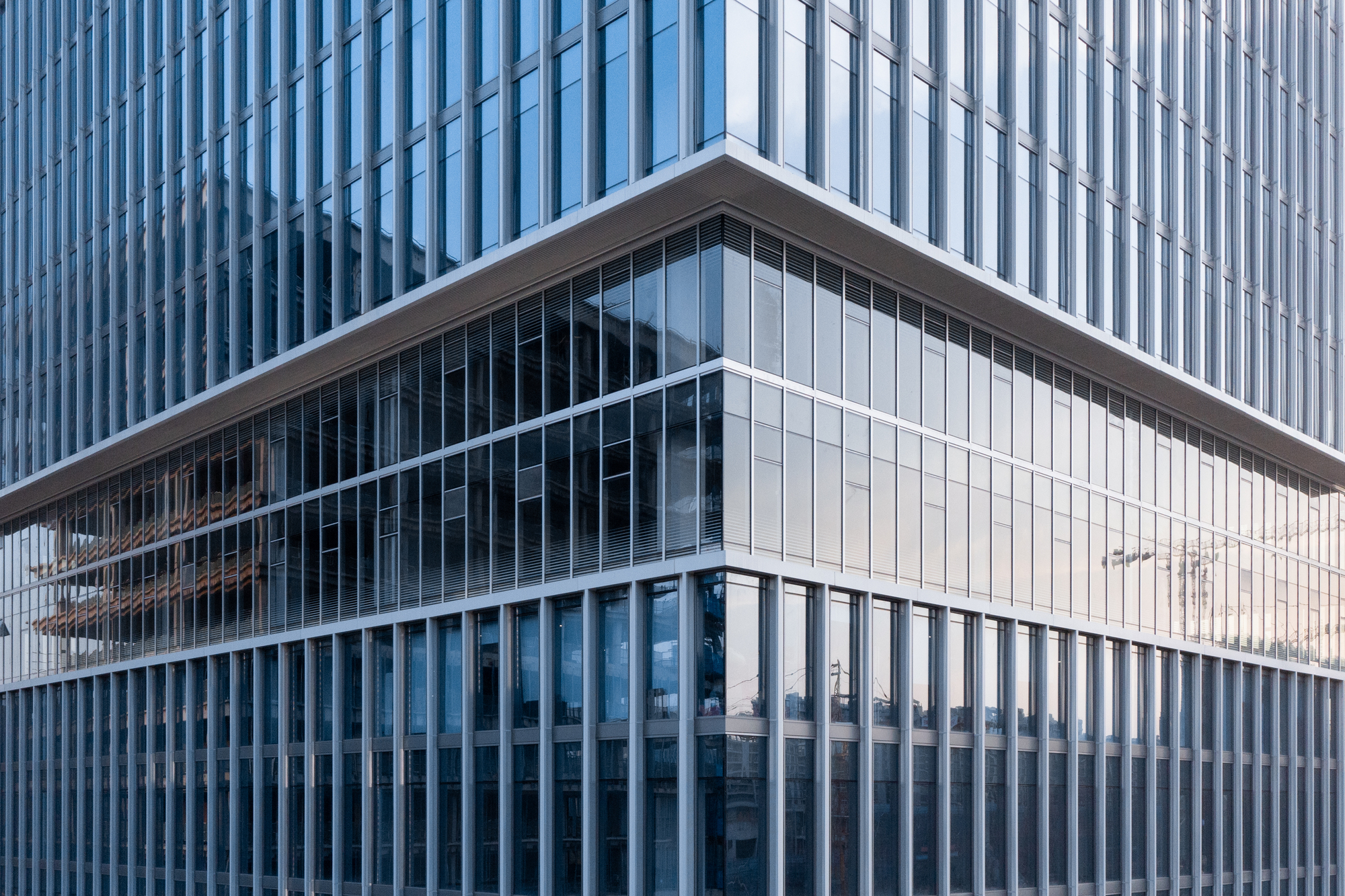 Cantilevered glass volume set between vertical aluminum louver screens on upper and lower levels