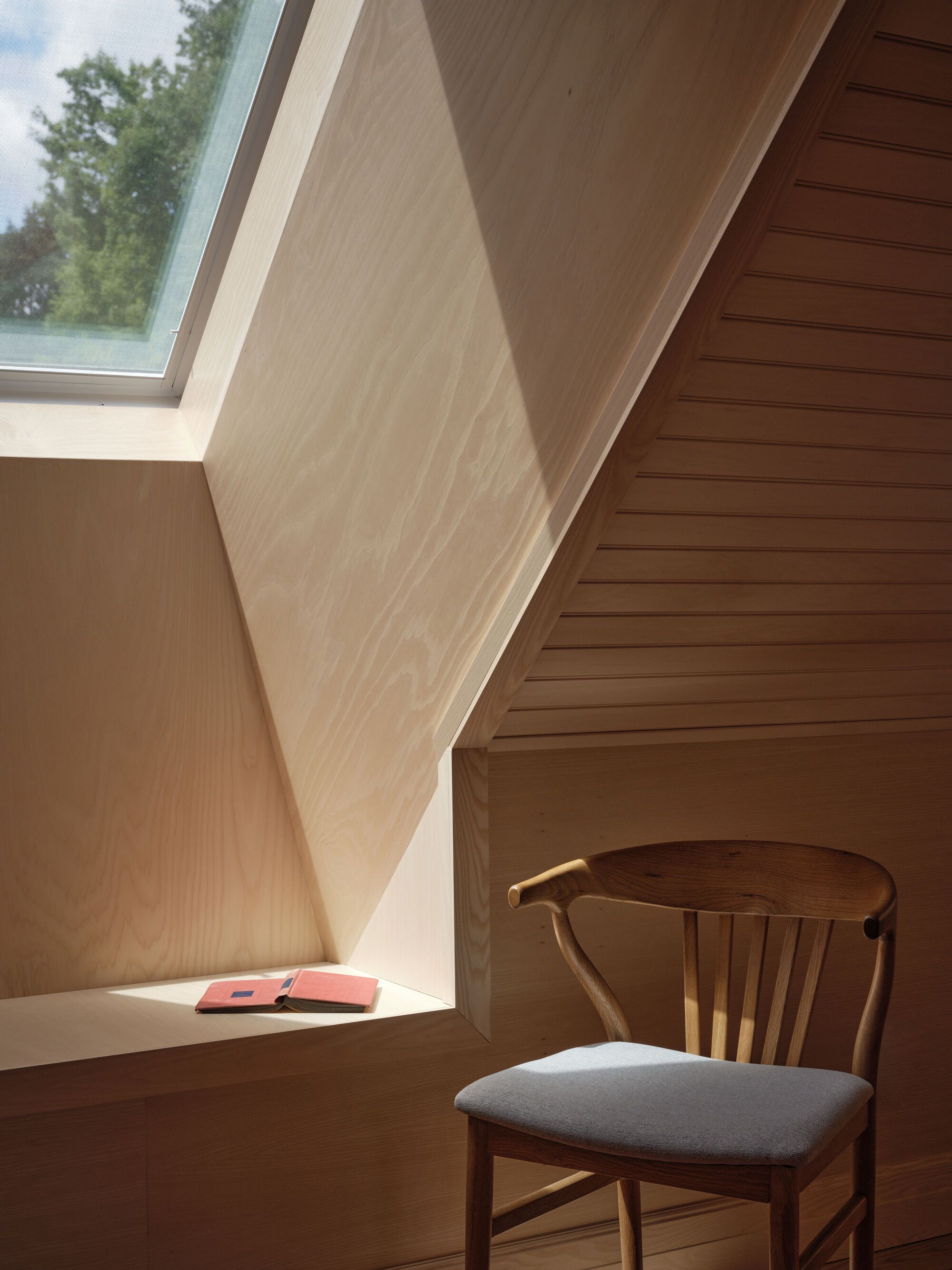 Built-in window nook with timber paneling and skylight casting daylight onto a reading chair