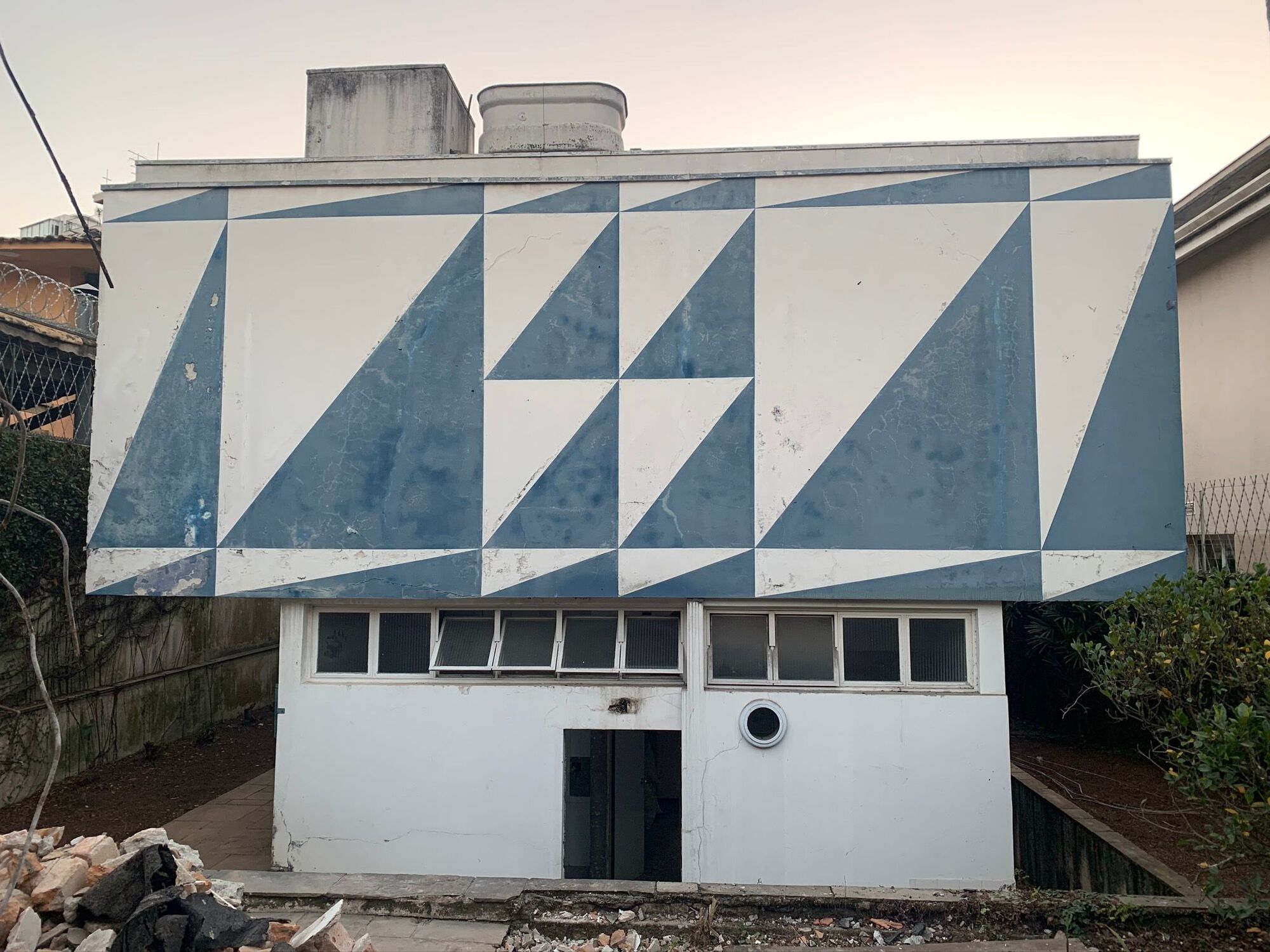 Rear elevation showing blue and white diagonal tile pattern above lower level windows at dusk