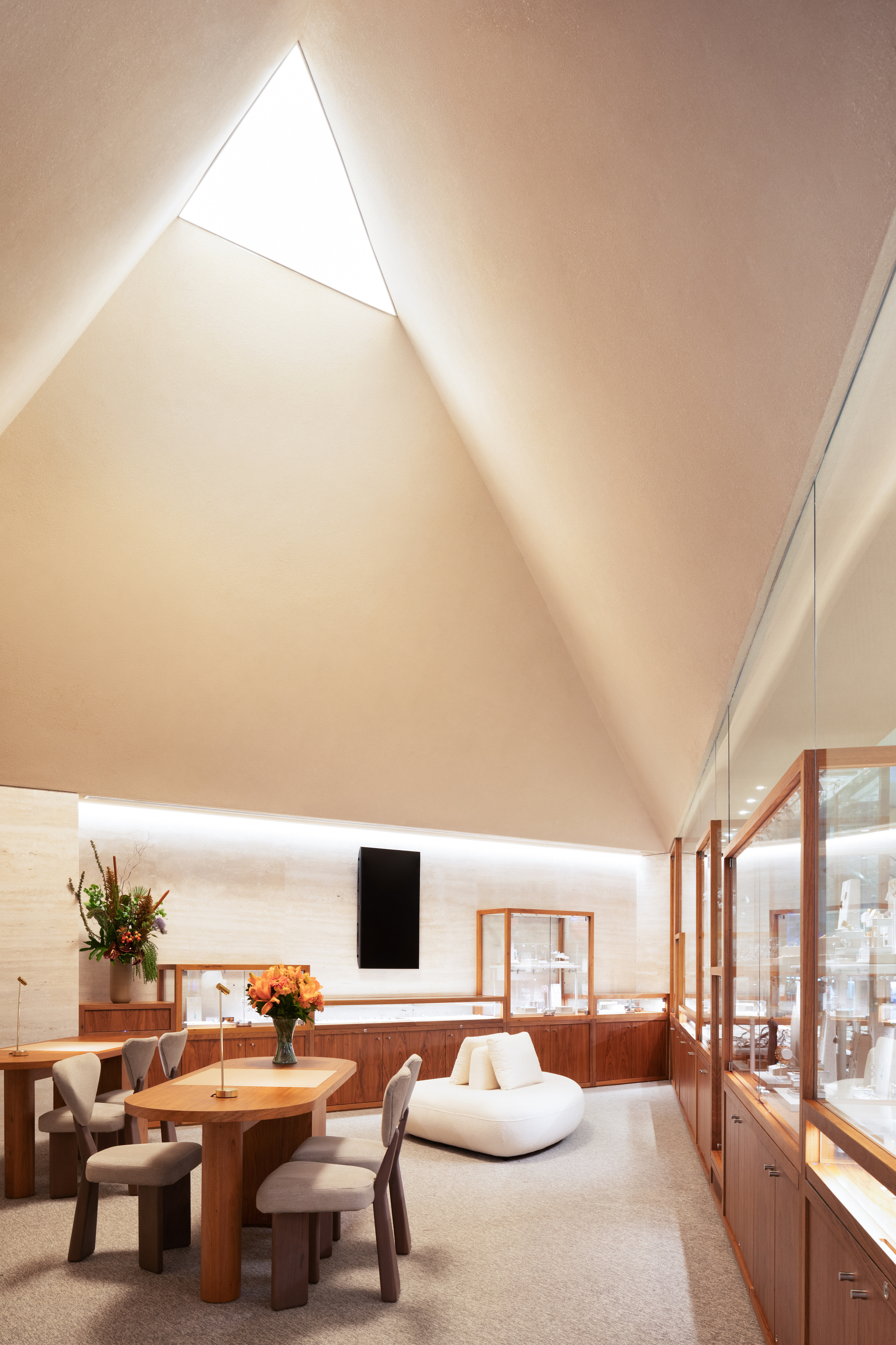 Triangular skylight with backlit cove illuminating the pitched ceiling above the seating area