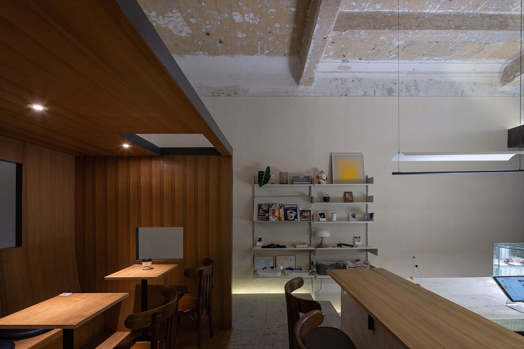 Interior view showing timber box volume with recessed lighting and white shelving against plaster walls
