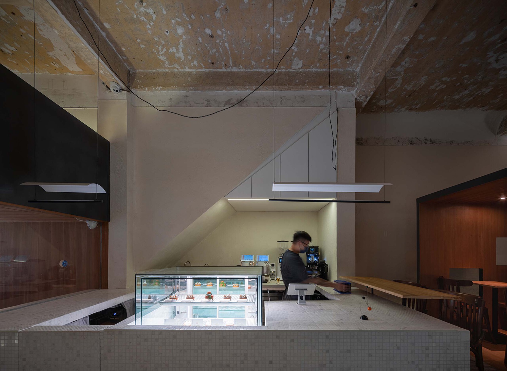 Service counter with glass display case and tile surround under an exposed concrete beam ceiling