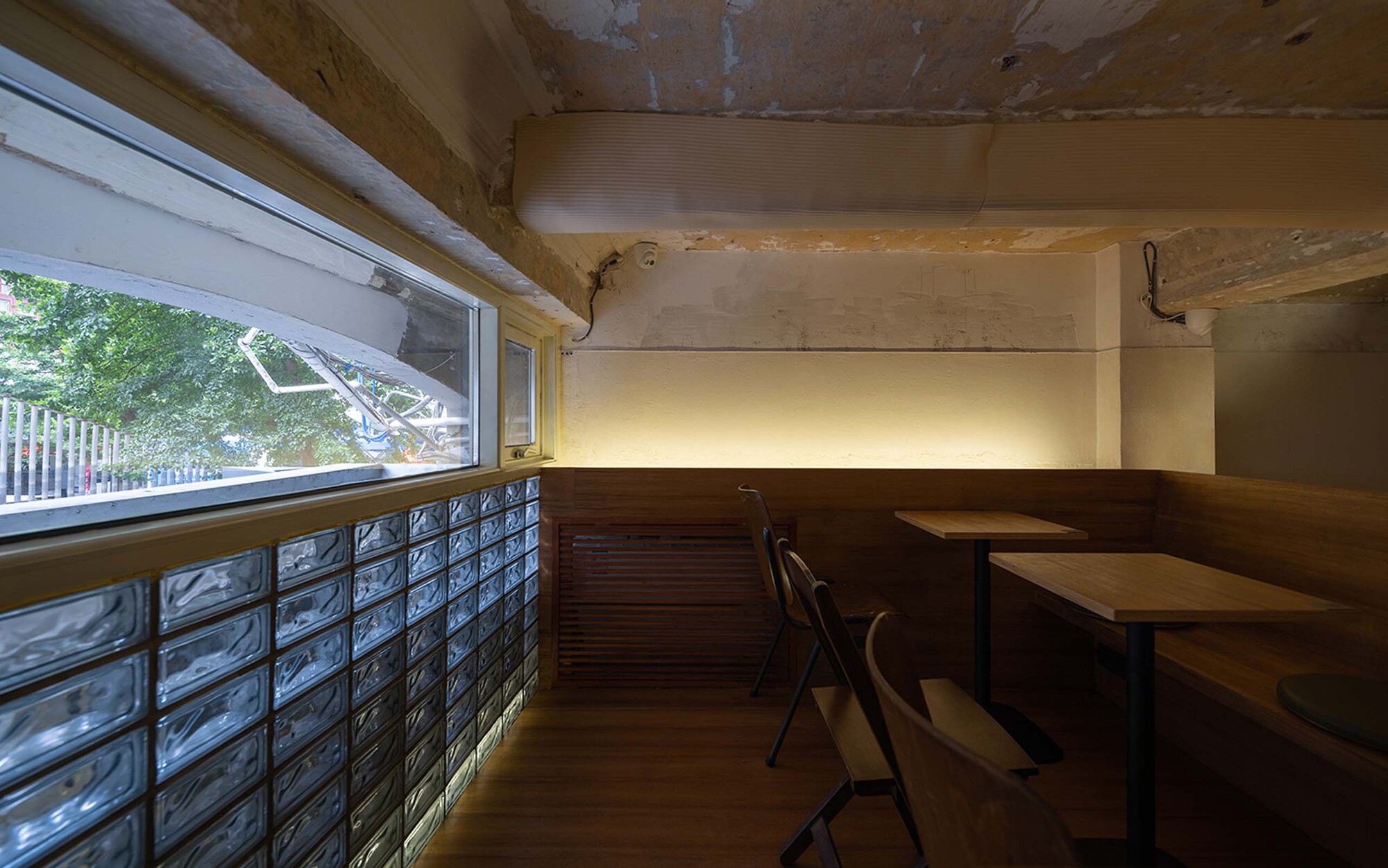 Seating nook with glass block window wall and timber banquette beneath a vaulted ceiling