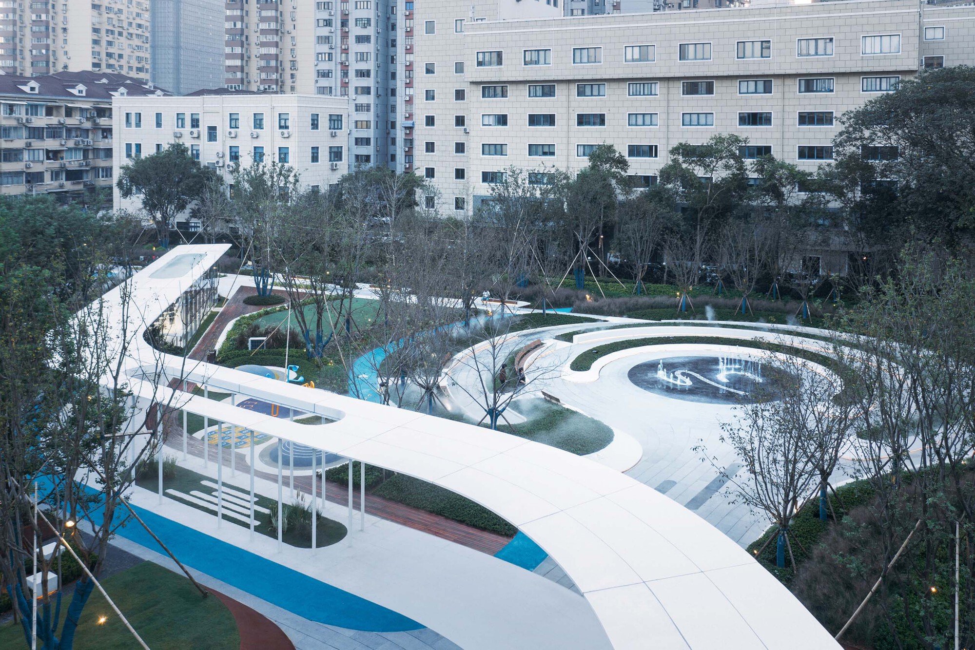 Elevated view of the white curving canopy threading through landscaped zones with newly planted trees