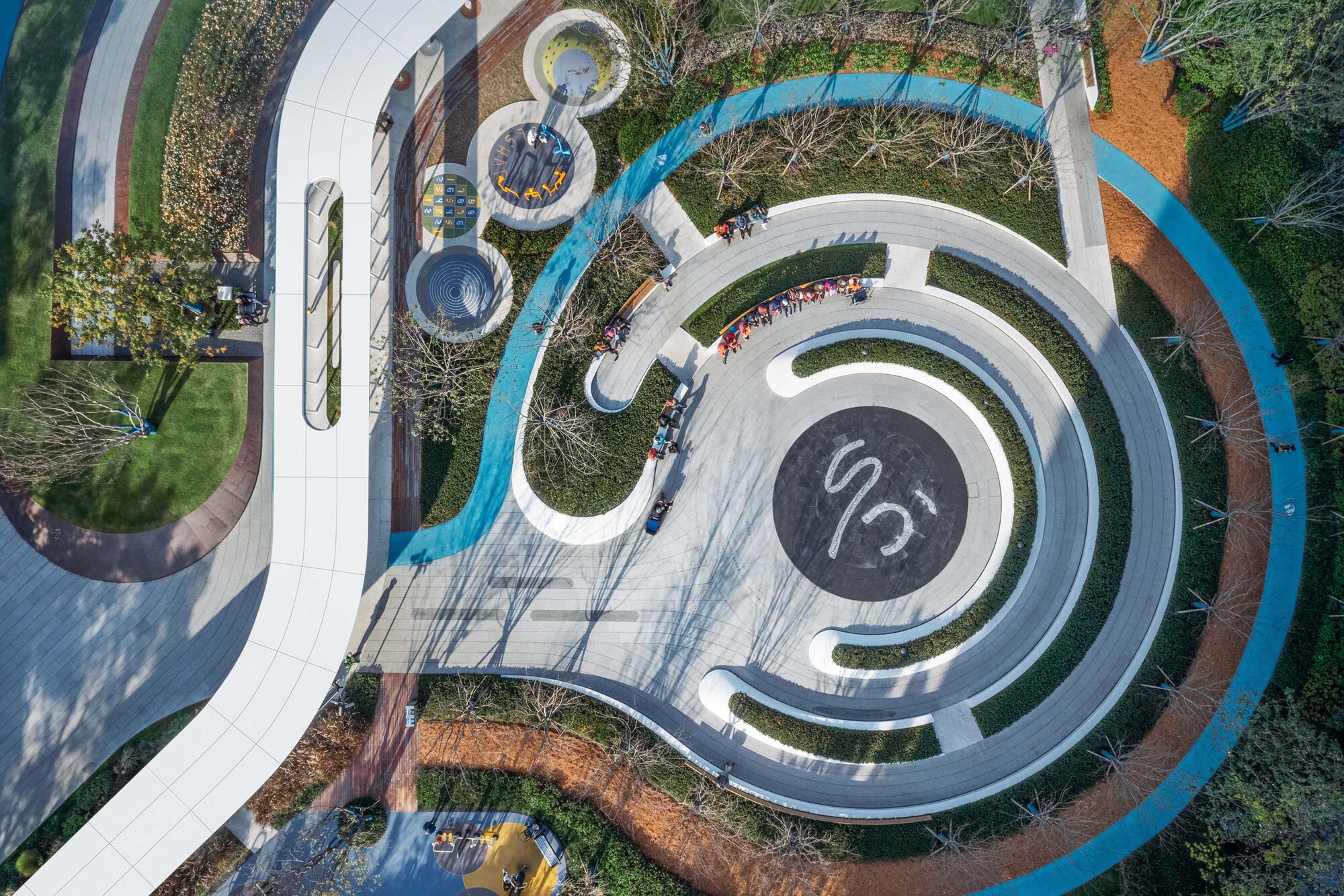 Drone view of the concentric white paving rings surrounding a central dark circle with people gathered