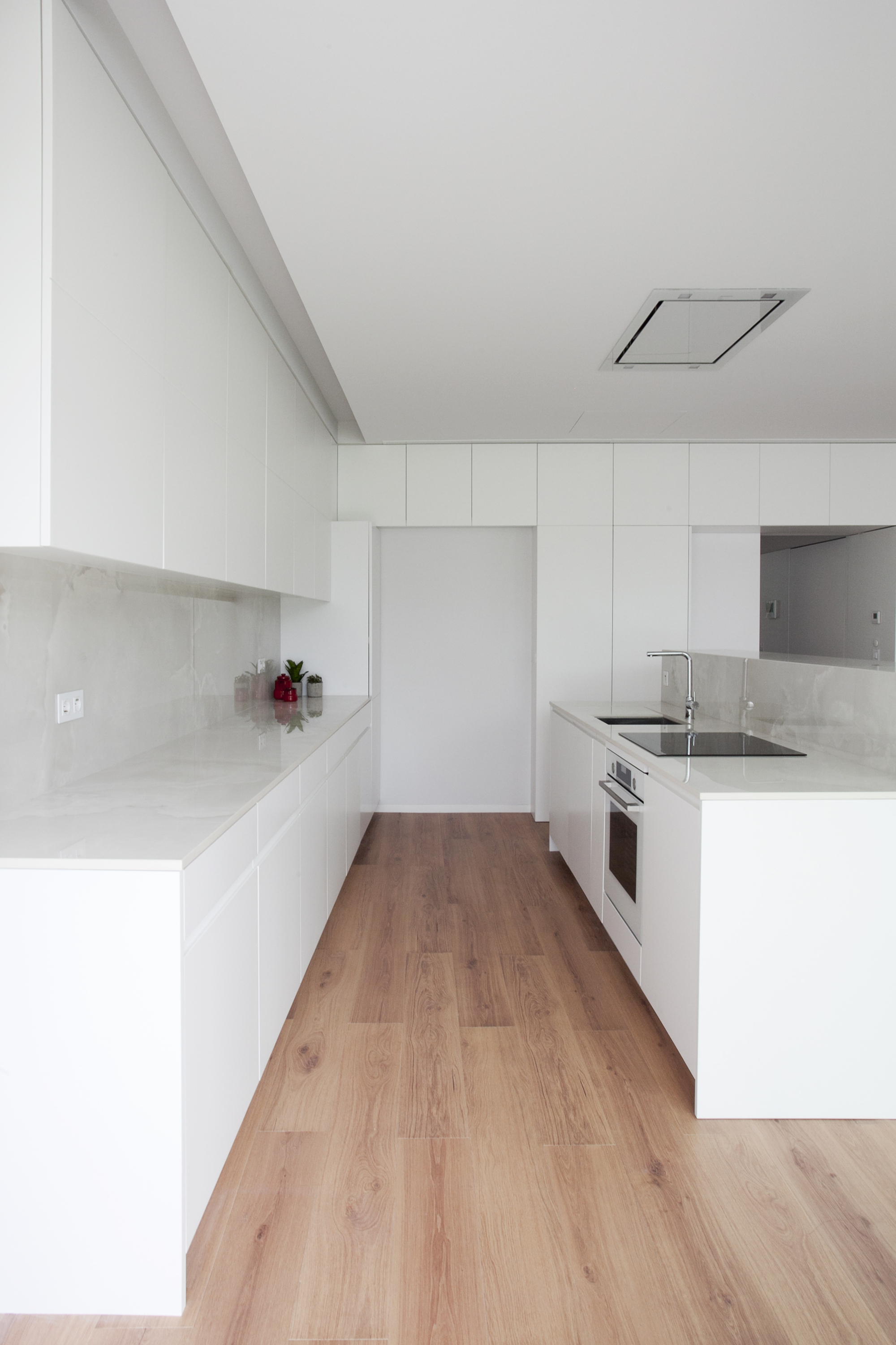 White kitchen with handleless cabinetry, recessed ceiling vent and pale timber flooring