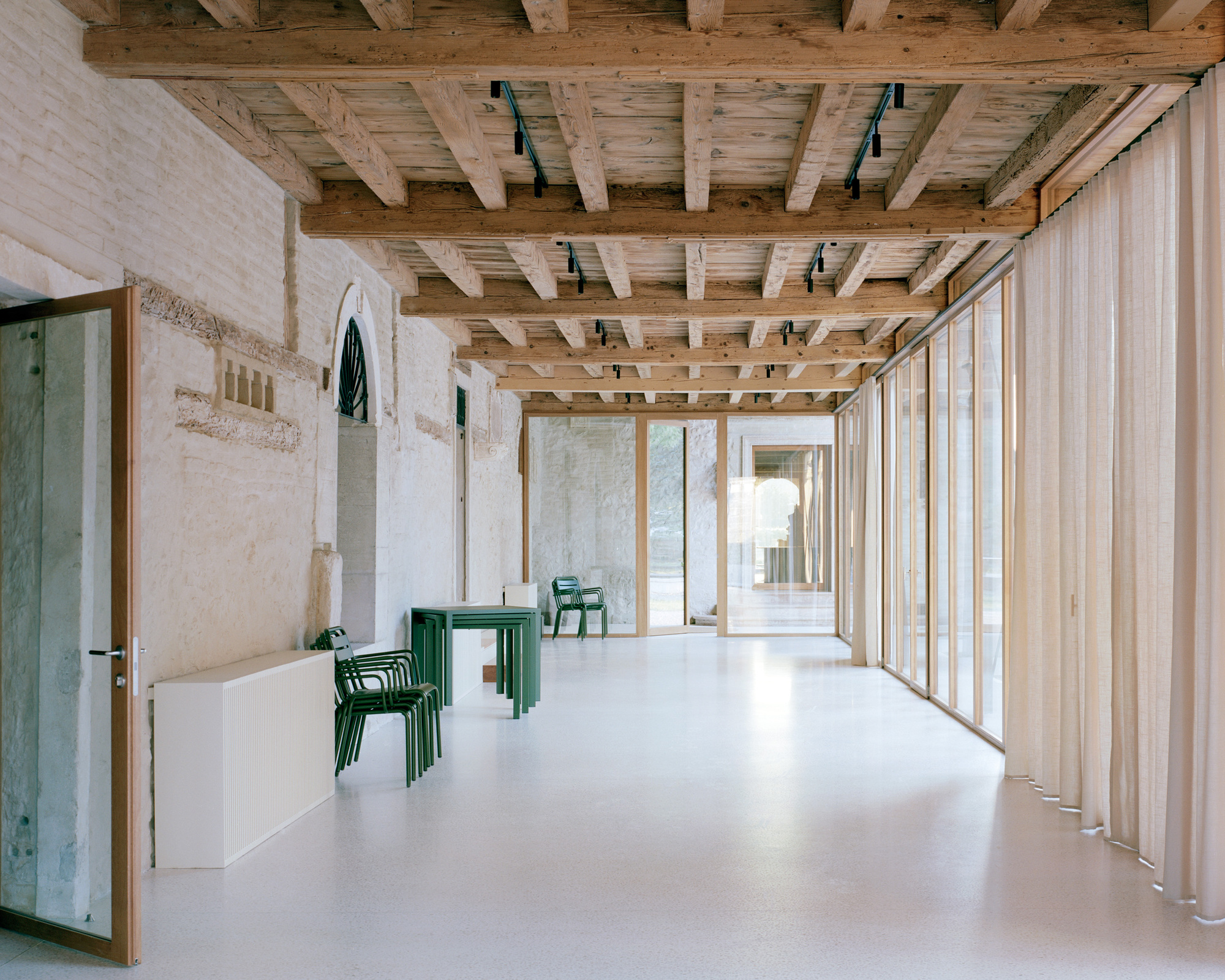 Interior corridor with exposed timber beam ceiling and vertical timber cladding along white resin floor