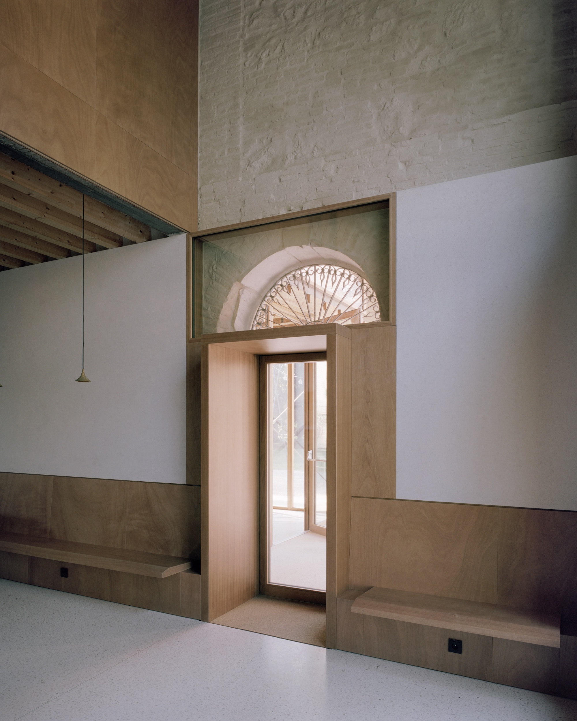 Interior view of timber-framed doorway with decorative fanlight in existing stone wall