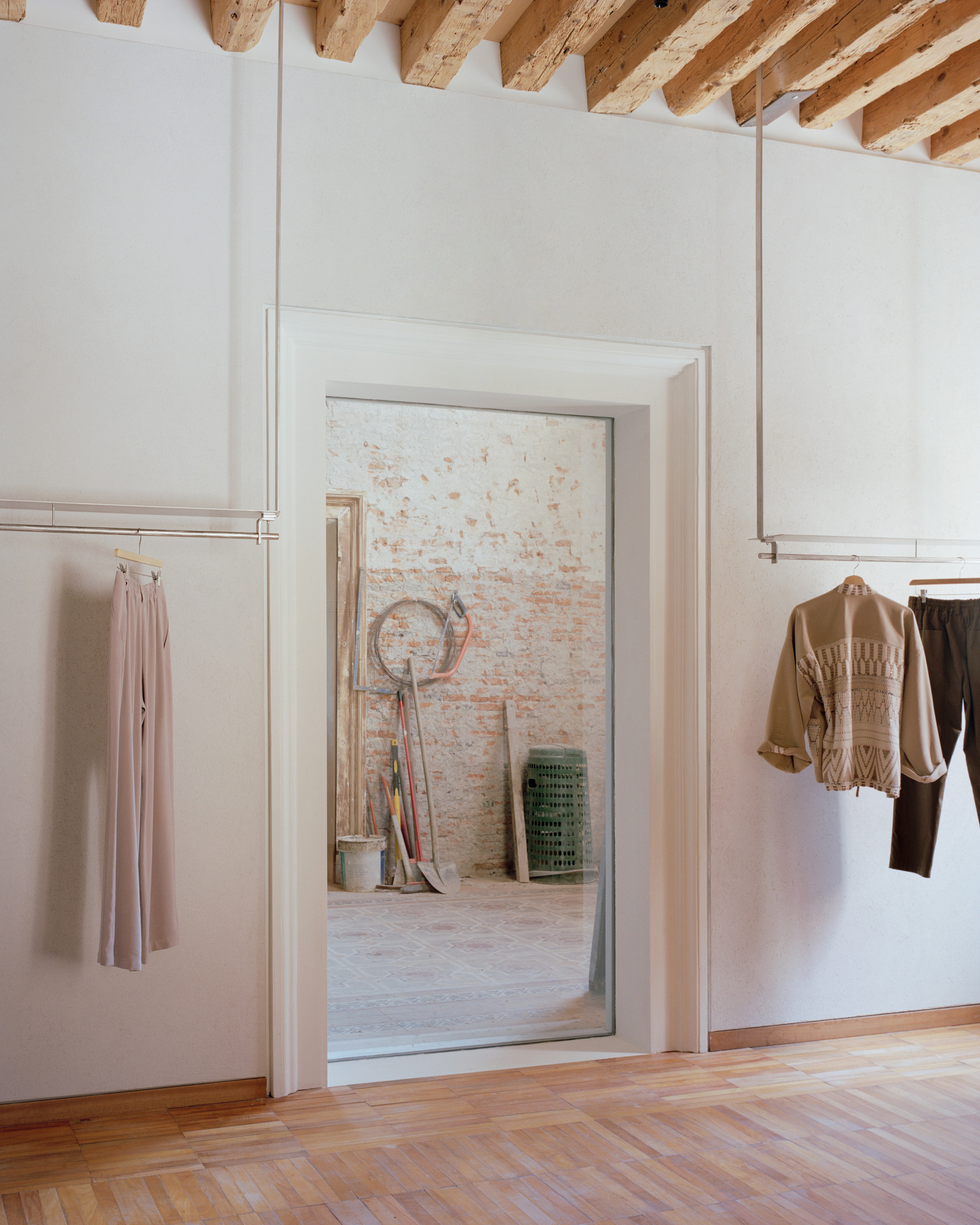Doorway framing view into room with painted white brick wall and herringbone wood flooring in foreground