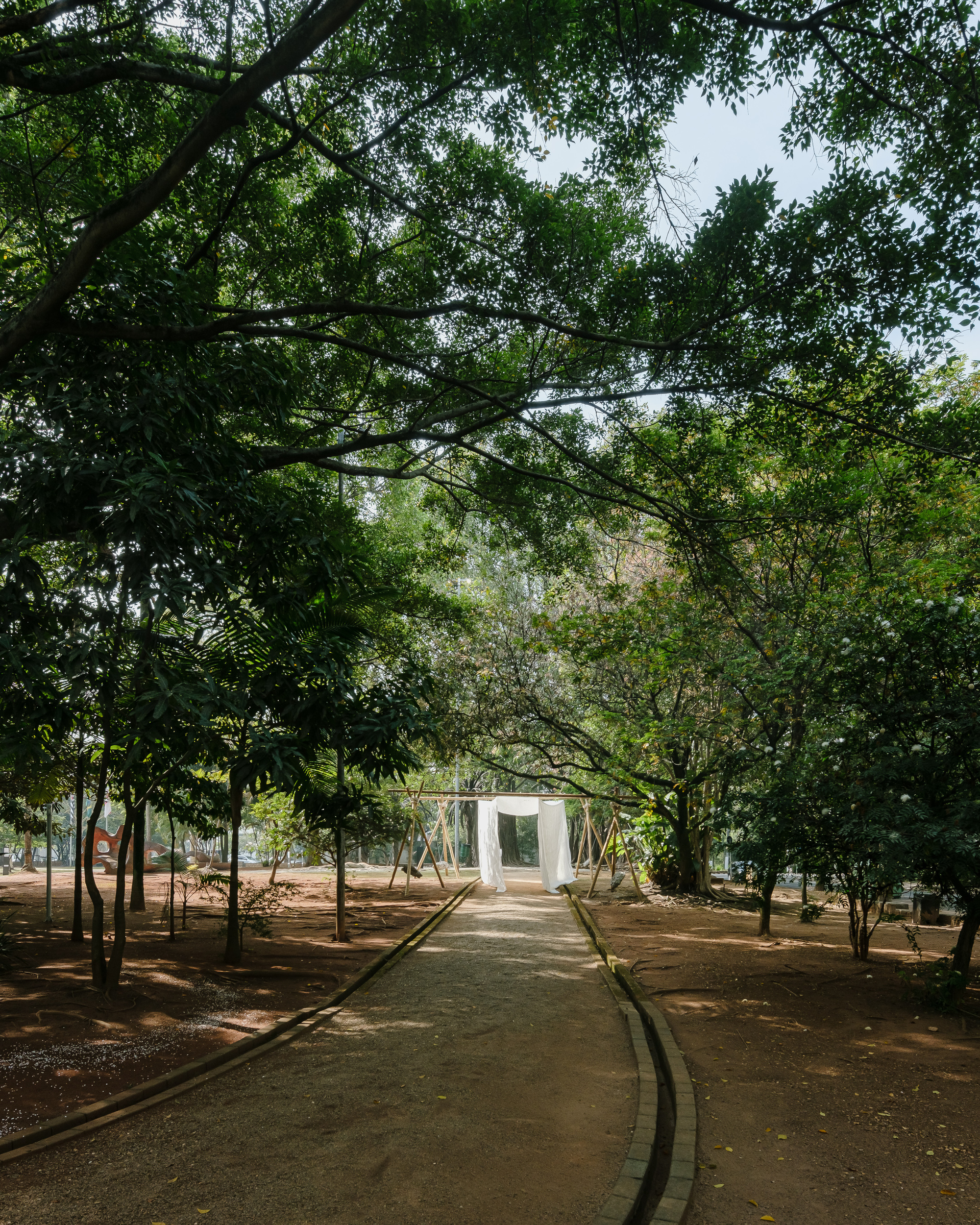 Path through a tree grove leading to a white cubic pavilion in the distance