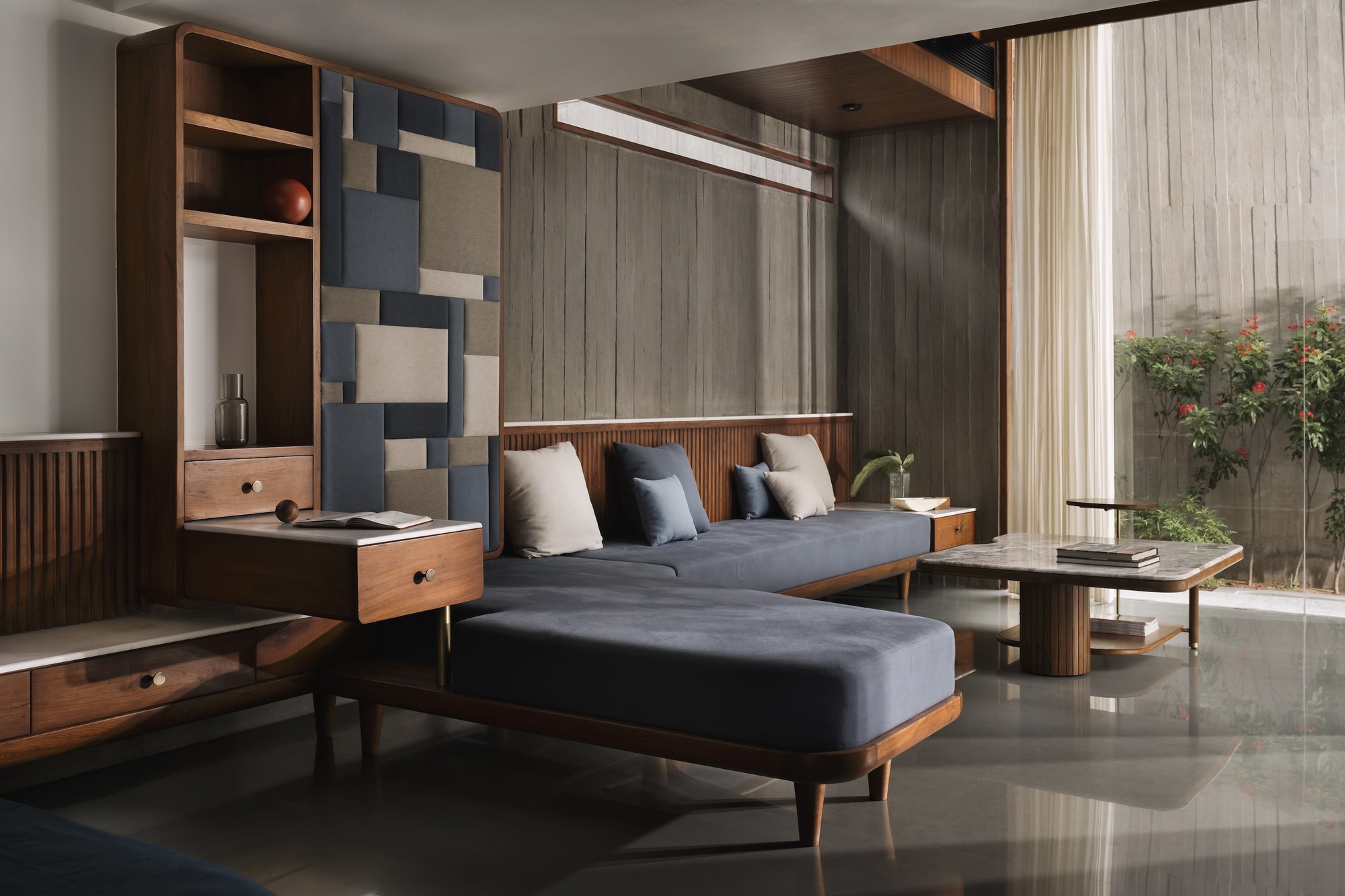 Living room with geometric wall panels, timber storage unit, and glazed doors opening to a planted courtyard