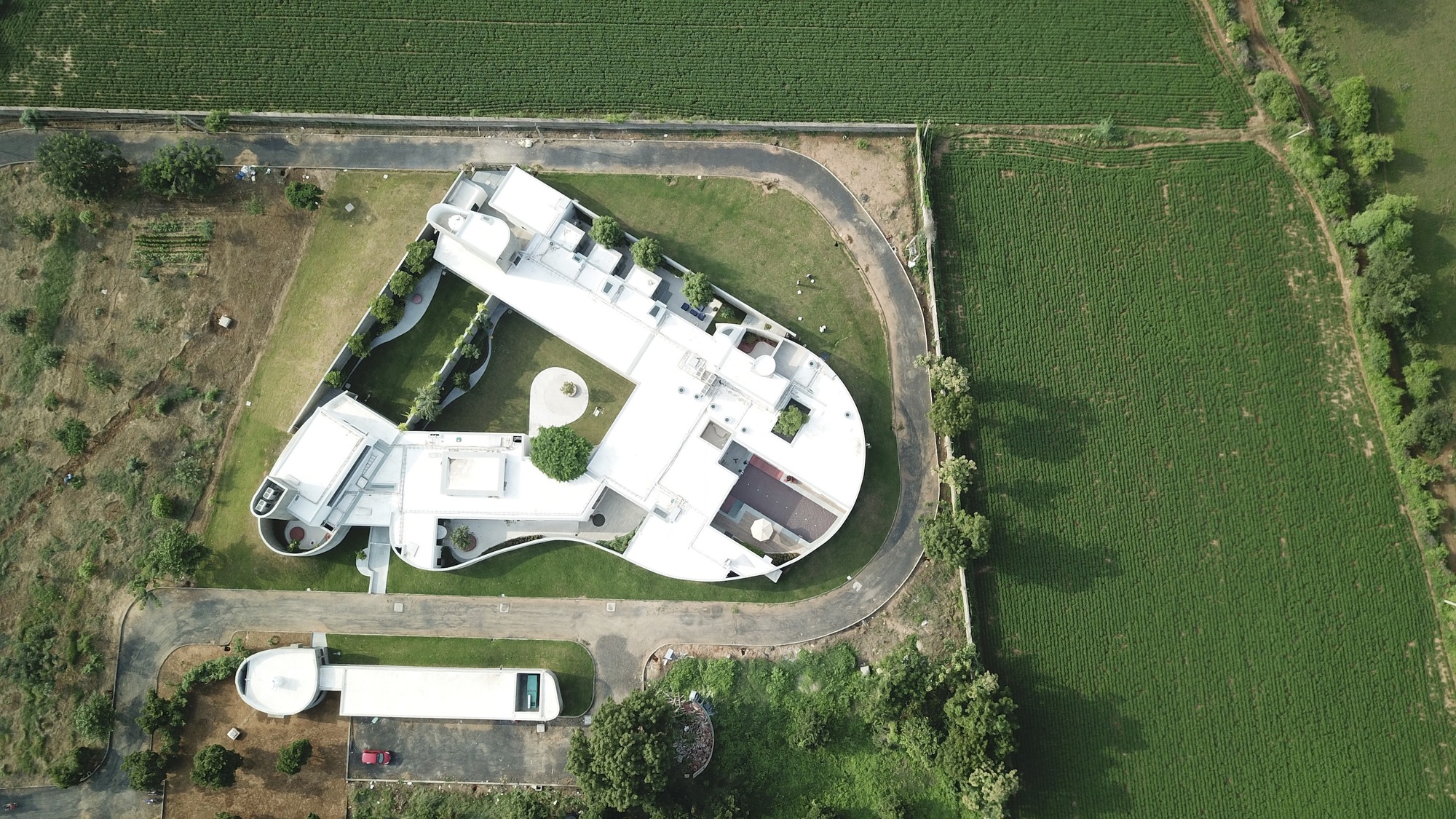 Aerial view of the curved white roof surrounded by agricultural fields and access roads