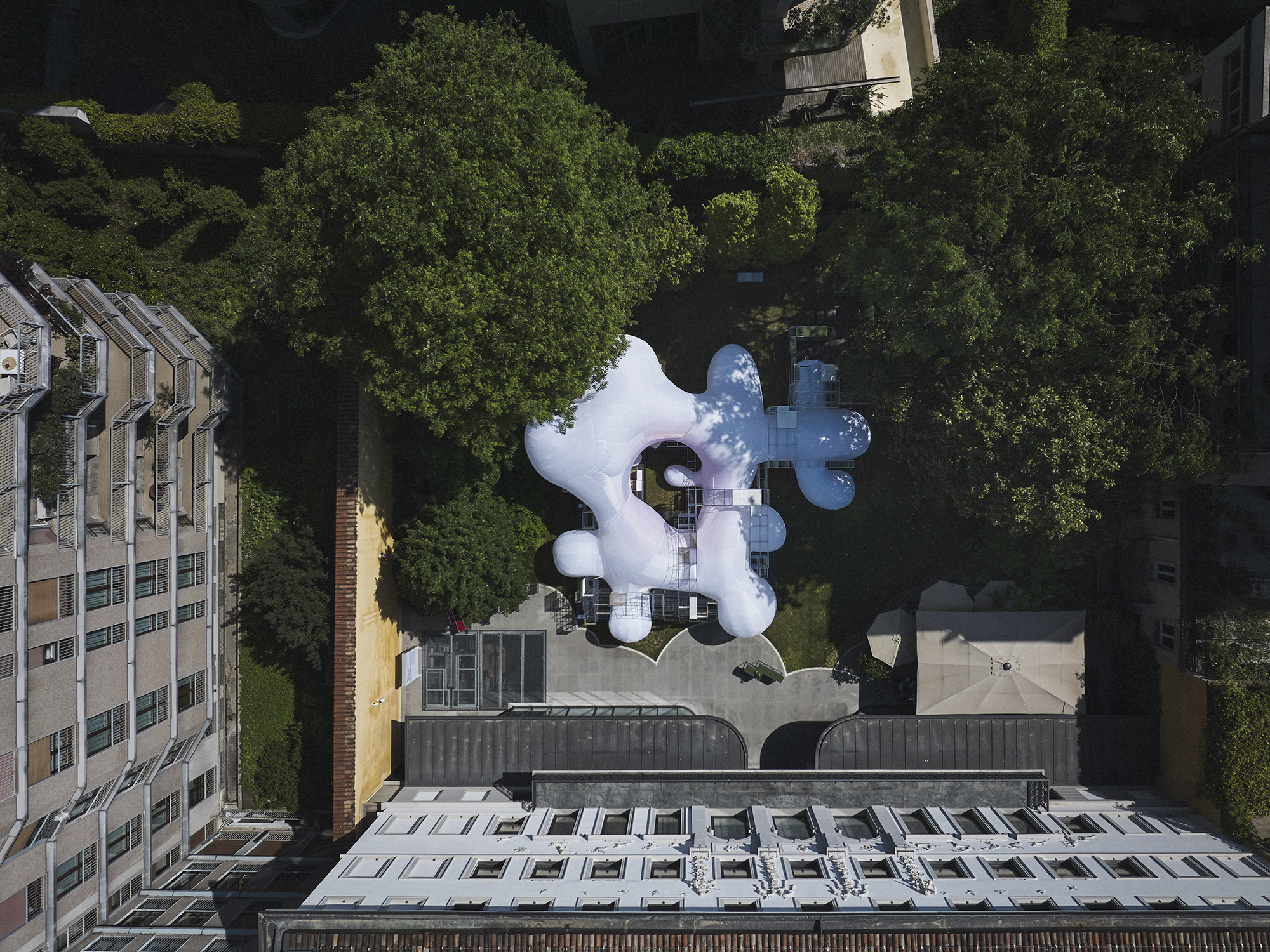 Aerial view of the white inflatable pavilion with three bulbous lobes set among green trees