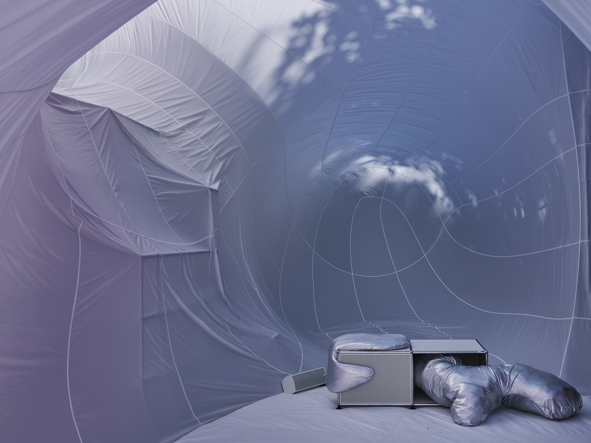 Interior view of the pale inflatable fabric with circular openings and clouds reflected on the surface