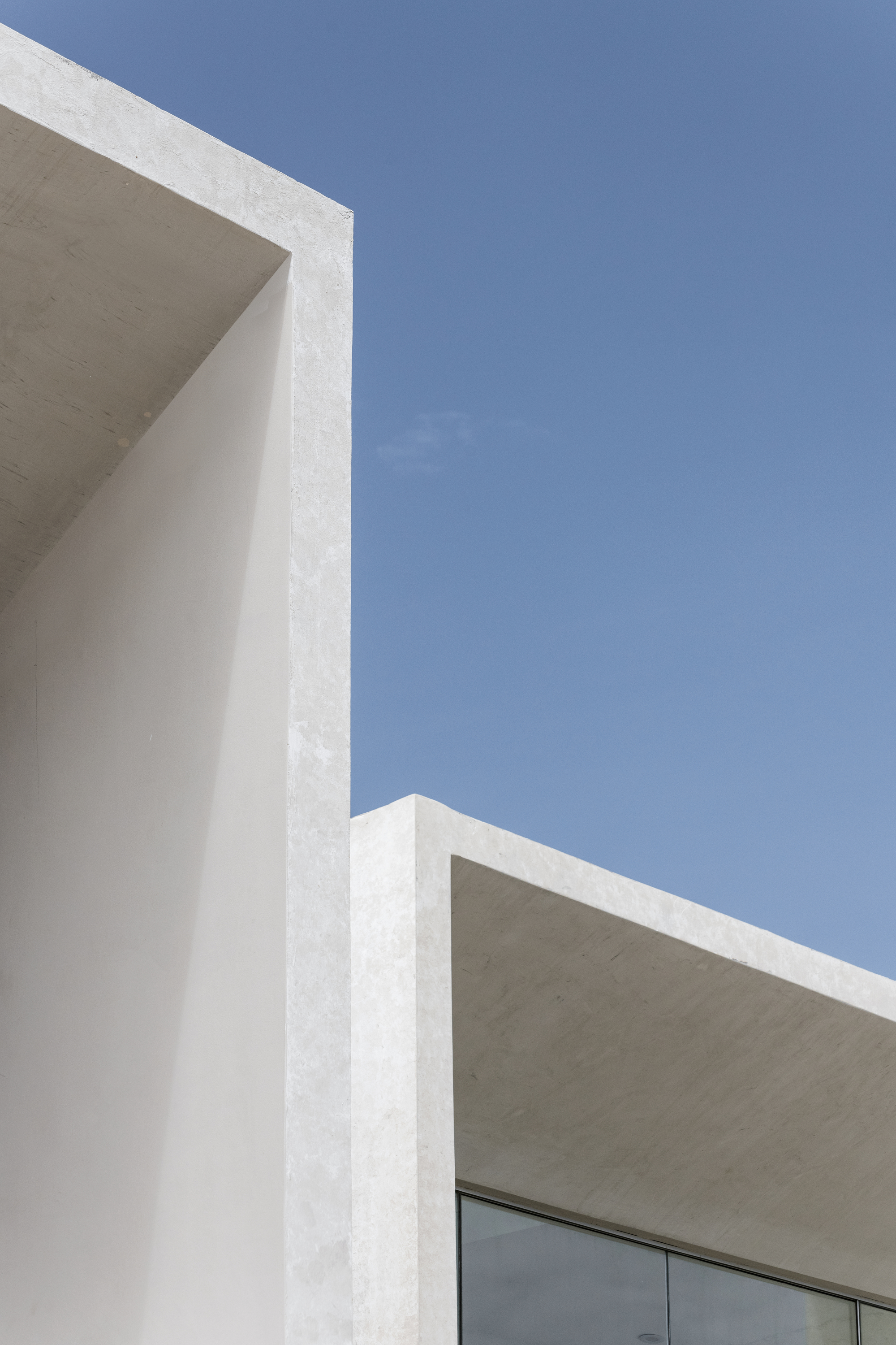 Close-up of white concrete roof edges and soffit against cloudless blue sky