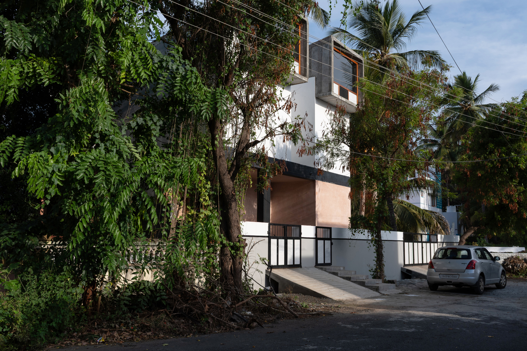 Street view of the white facade with concrete window boxes and palm trees overhead