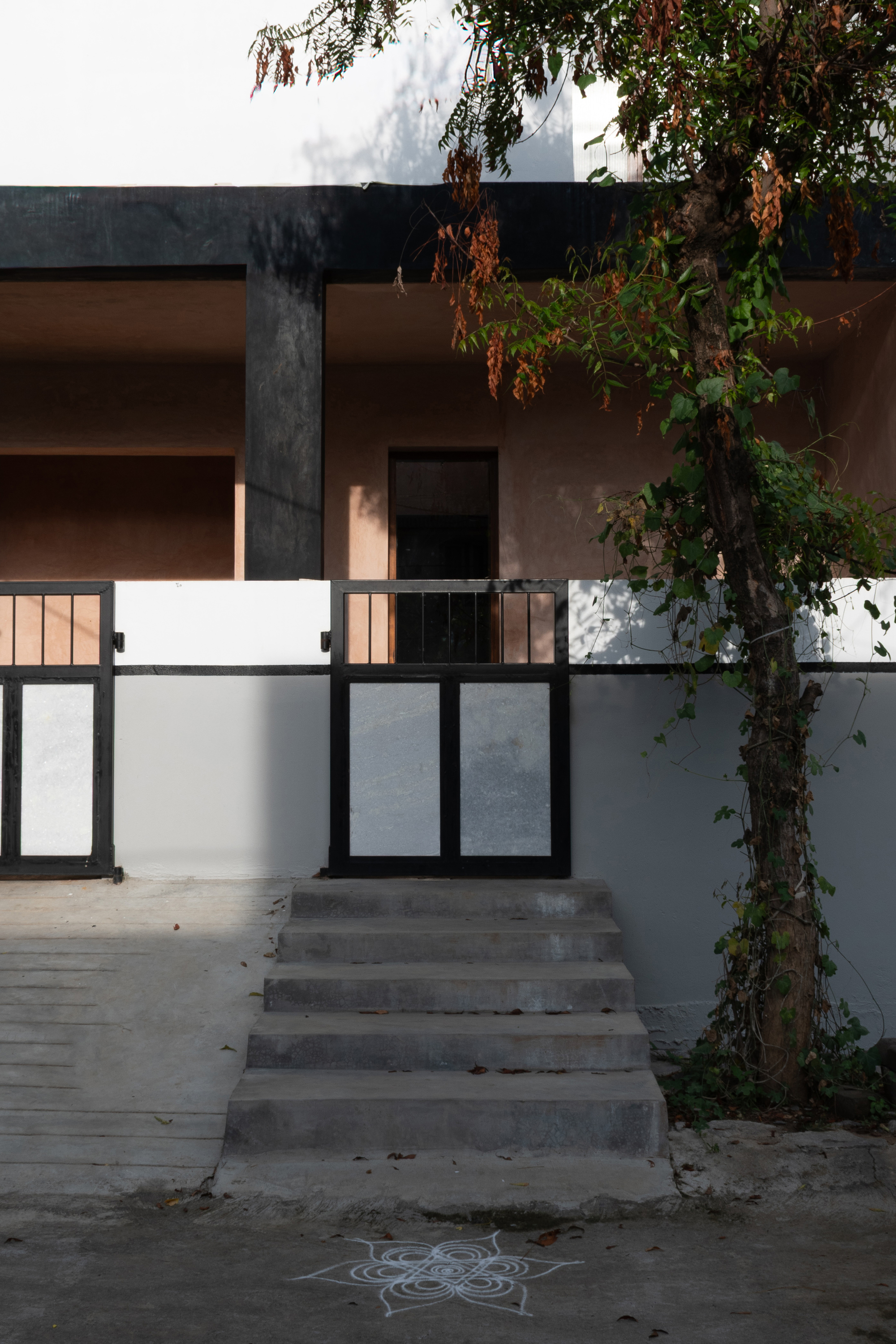 Street entrance with concrete steps and metal gate beneath a tree at dusk