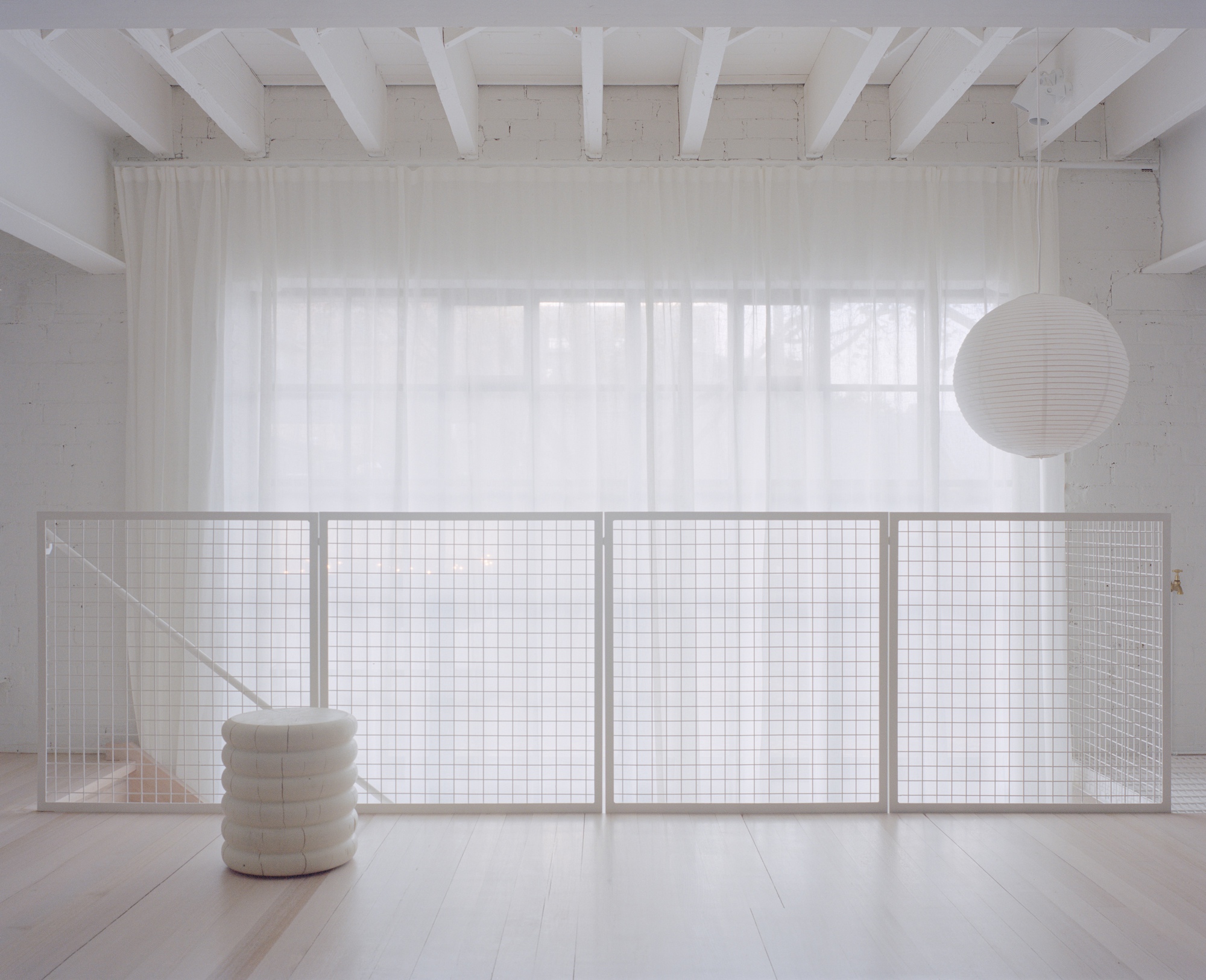 Interior mezzanine with wire mesh balustrade and white timber ceiling beams in diffused daylight