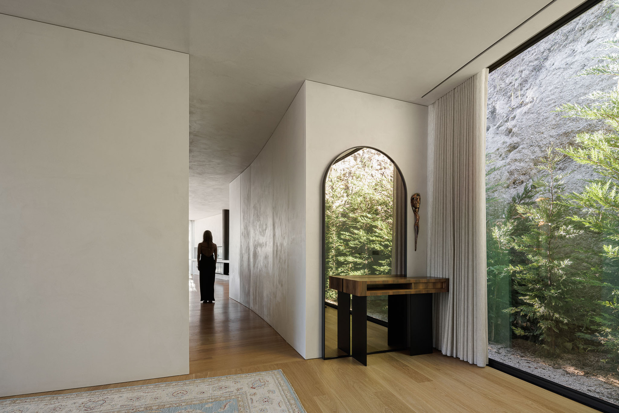 Interior corridor with curved plaster ceiling and arched mirror above console table near floor-to-ceiling window