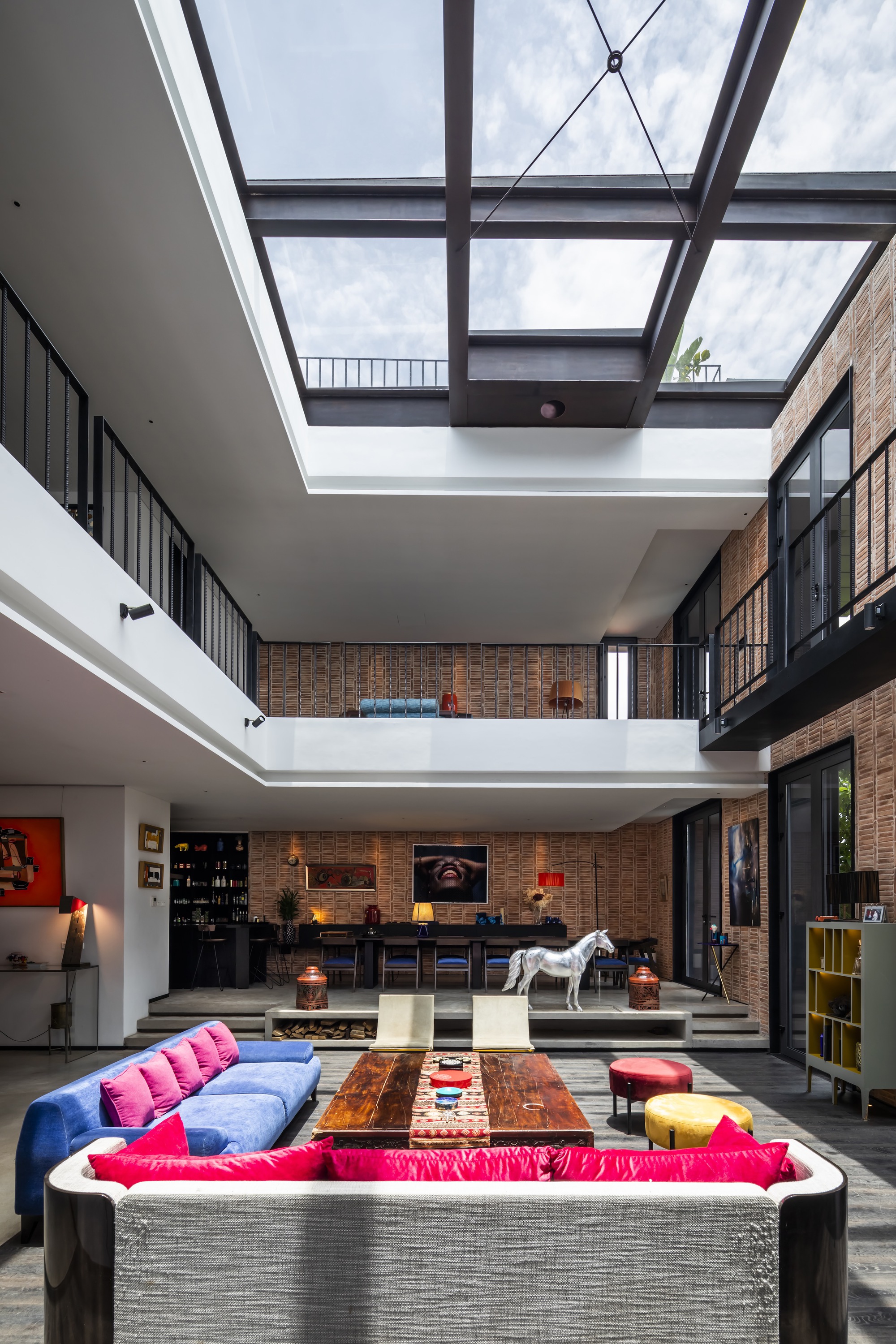 Double-height living space with exposed brick walls and a glazed steel skylight overhead