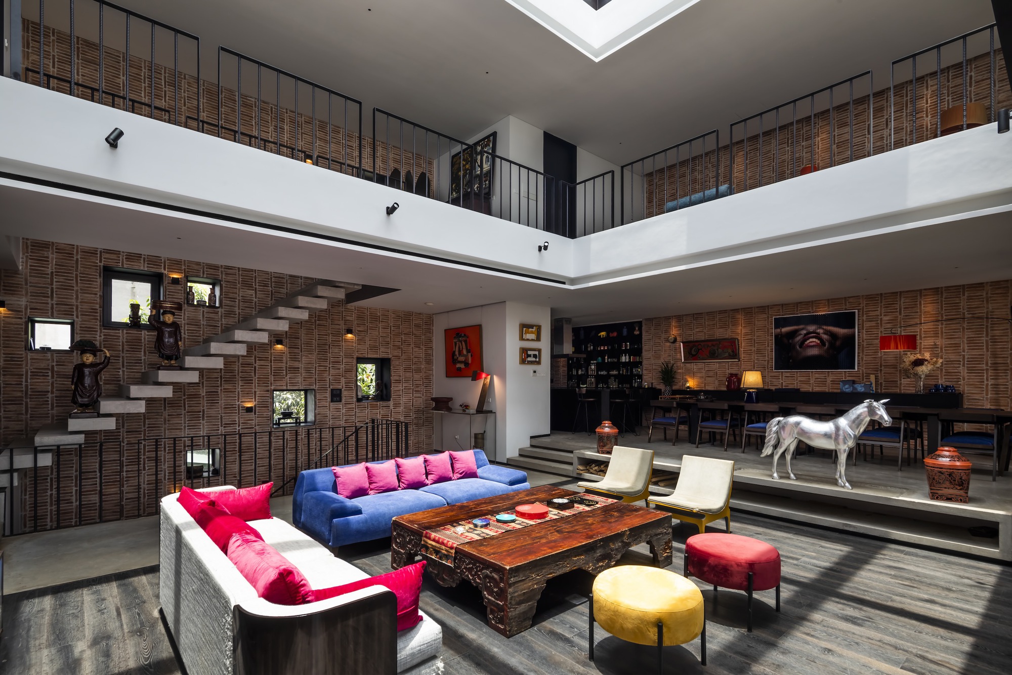 Floating staircase against the textured brick wall rising through the multi-level interior void