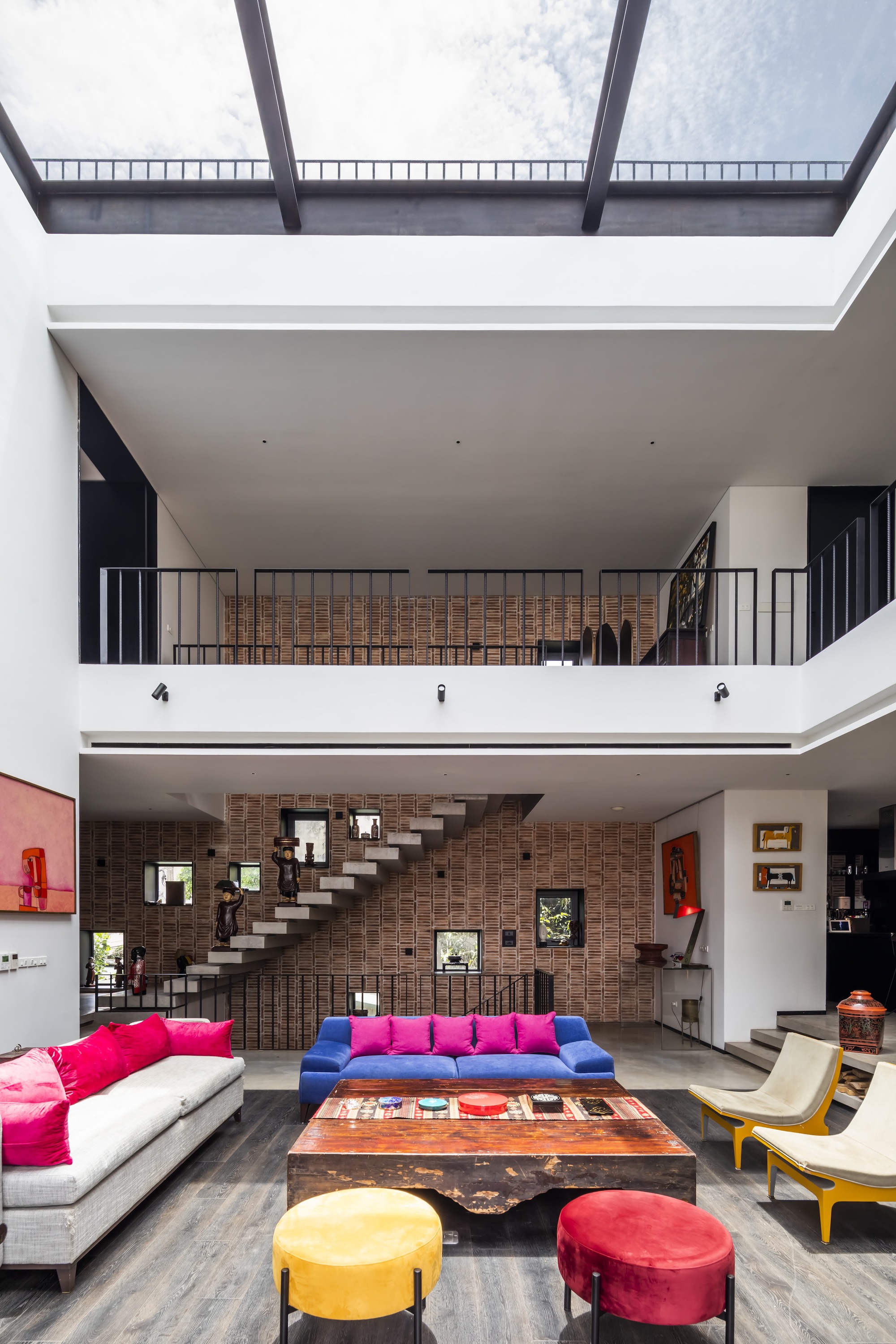 Central void framed by white balconies and a continuous skylight bringing diffused daylight down
