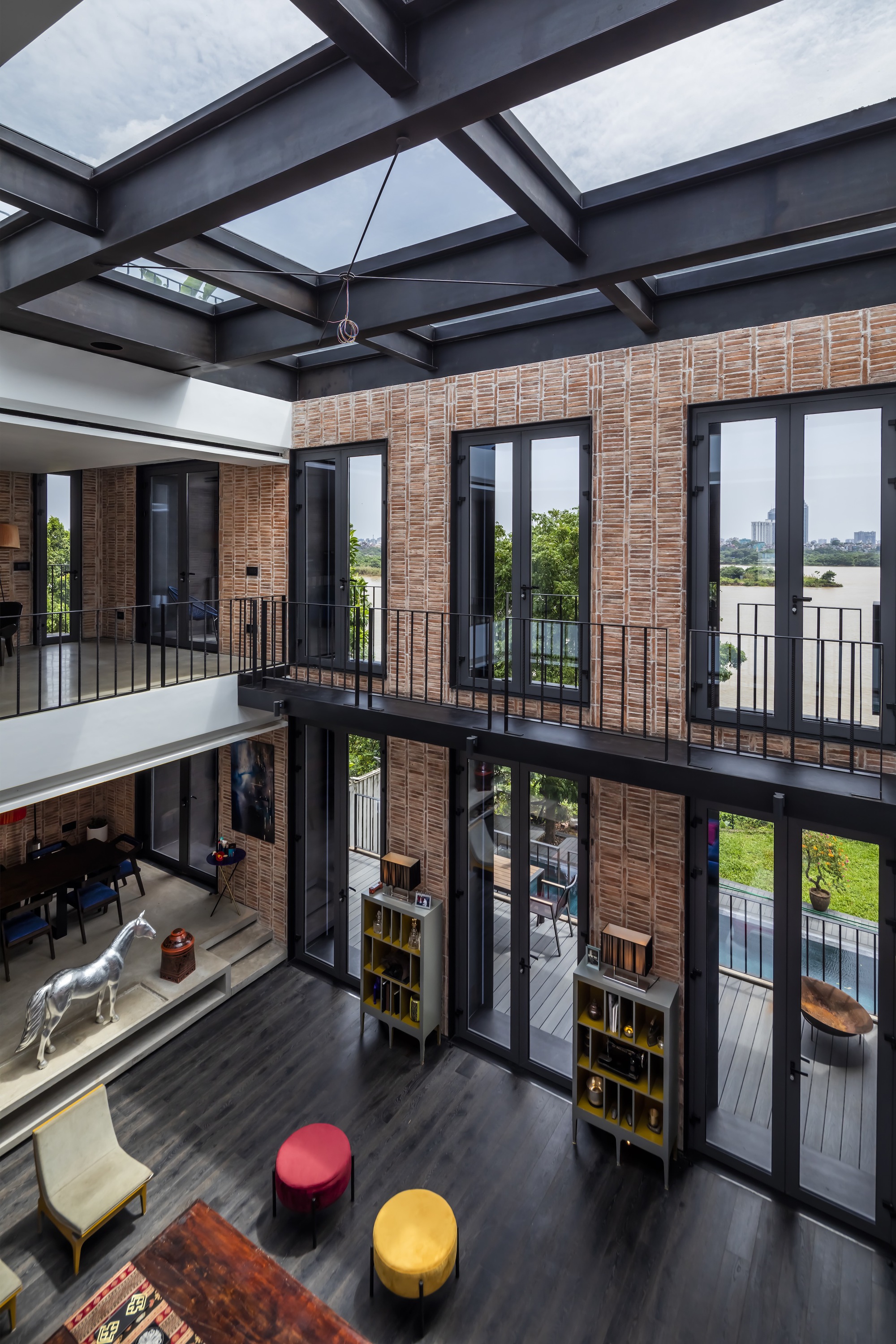 Upper level view with exposed steel beam ceiling, skylights and timber slat walls overlooking the living area