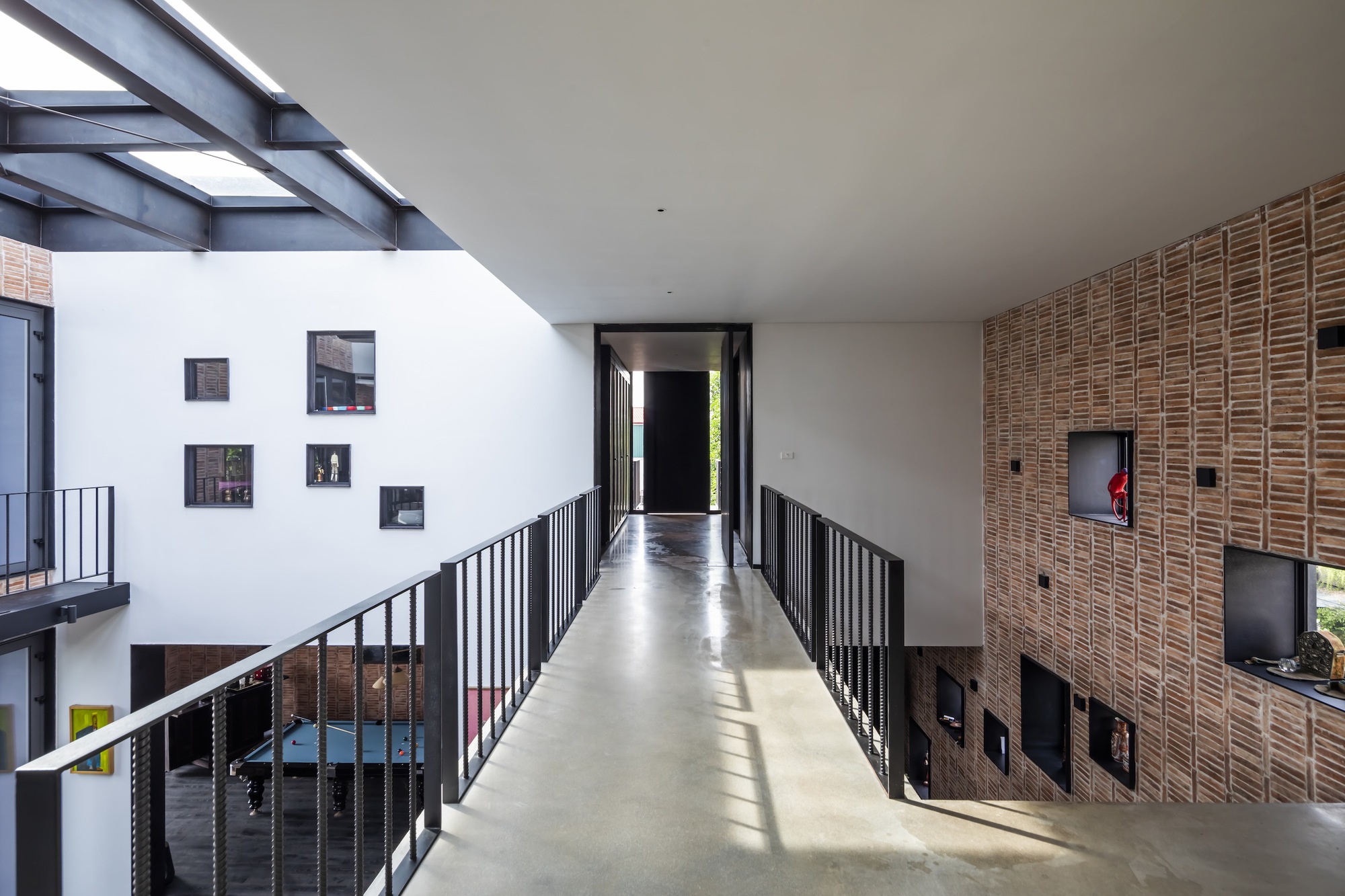Upper-level bridge with polished concrete floor, black steel railings and timber slat wall illuminated by skylight
