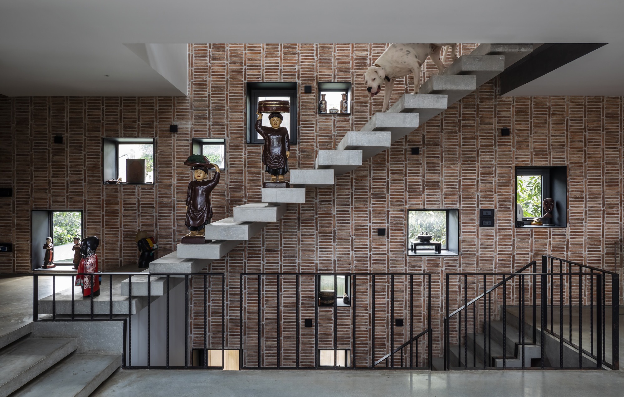 Cantilevered concrete stair treads against a perforated brick wall with residents in view