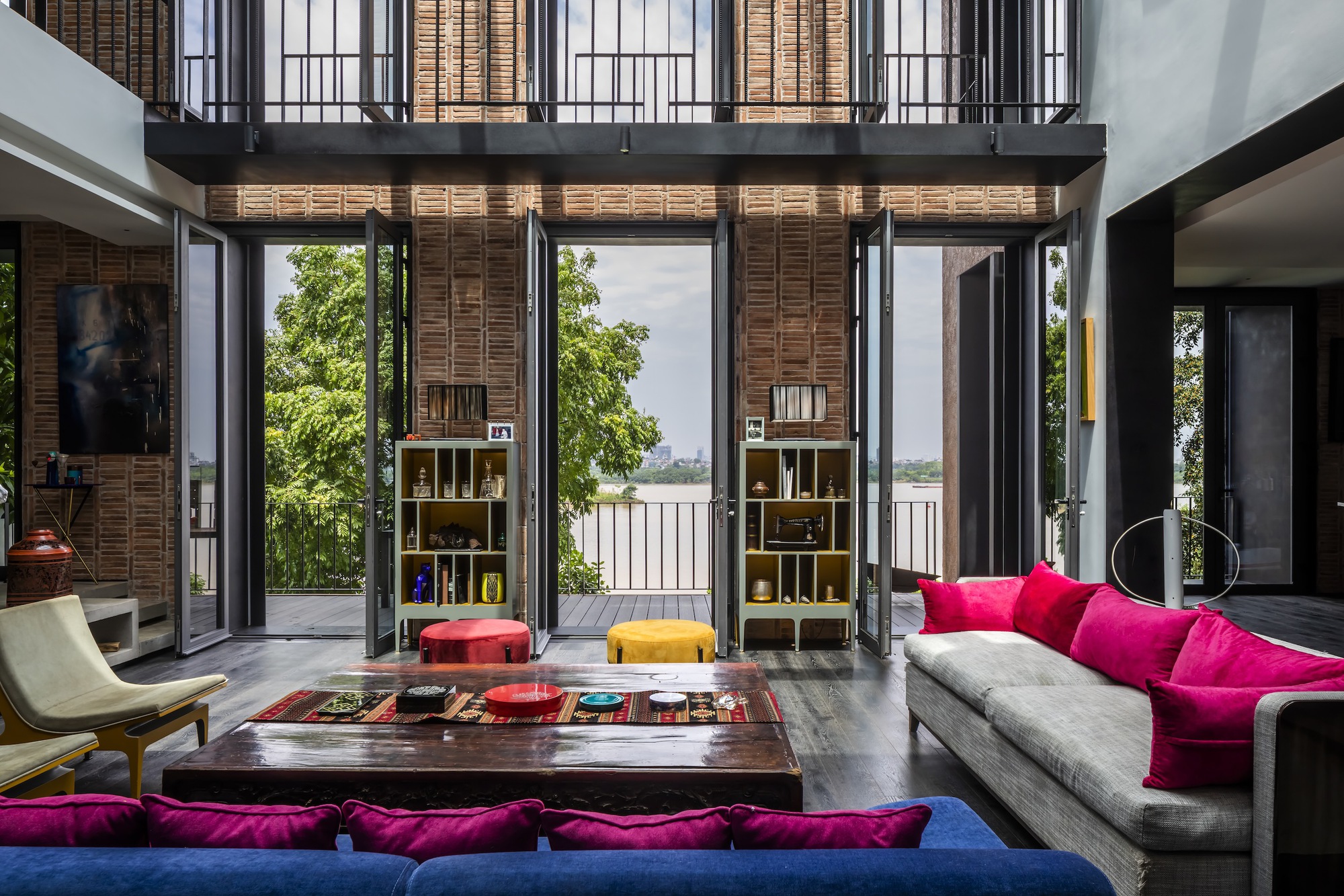 Open doors revealing outdoor terrace with water views beyond the double-height living space