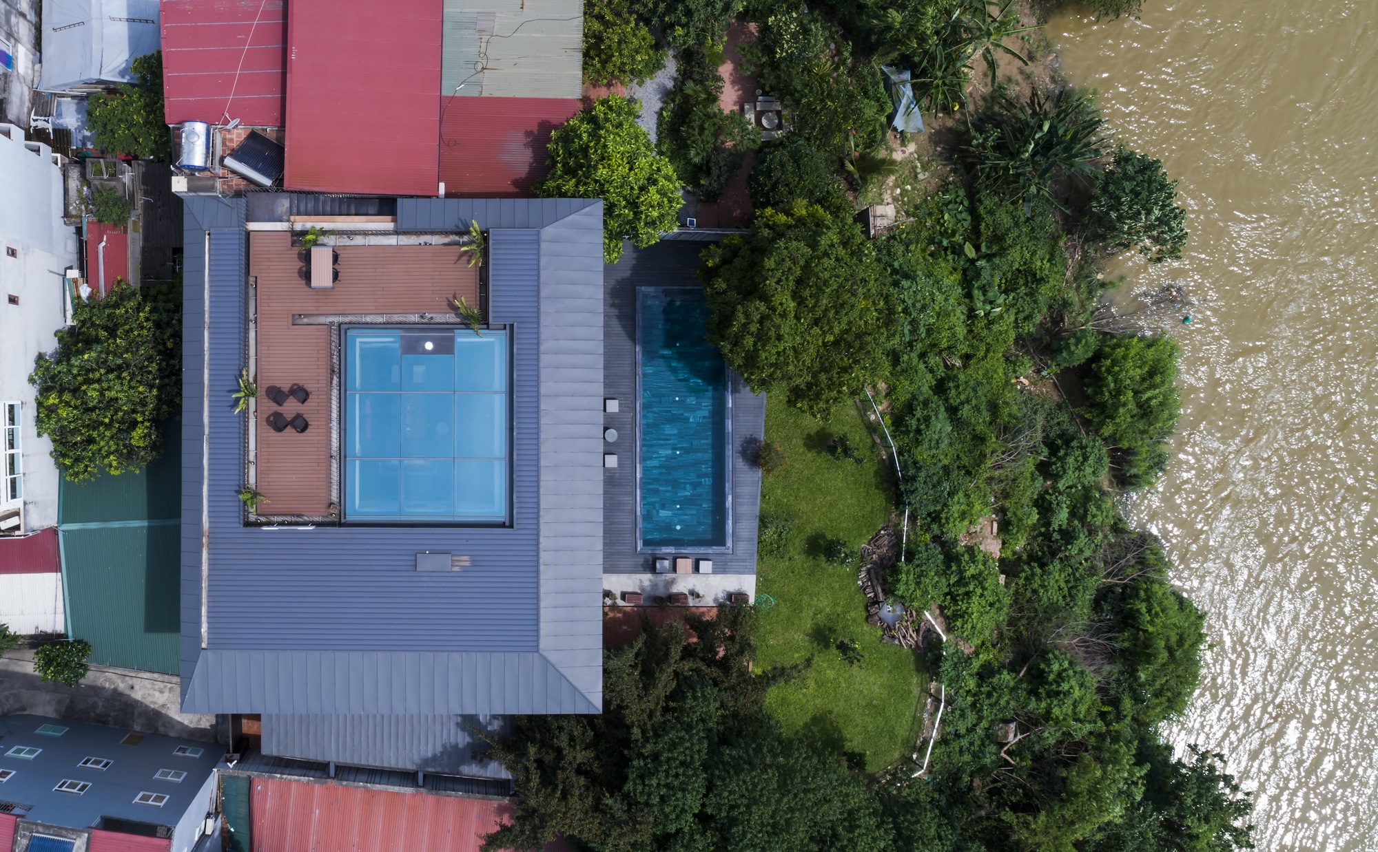 Aerial view of the cantilevered volume with swimming pool and terrace adjacent to a riverbank