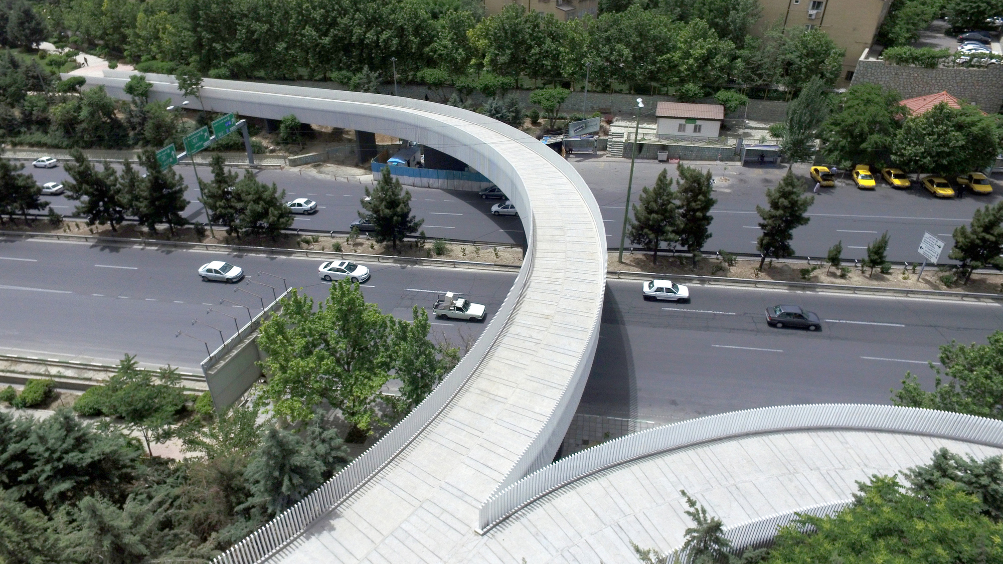 Deck of the curving footbridge with ribbed metal cladding above the roadway below