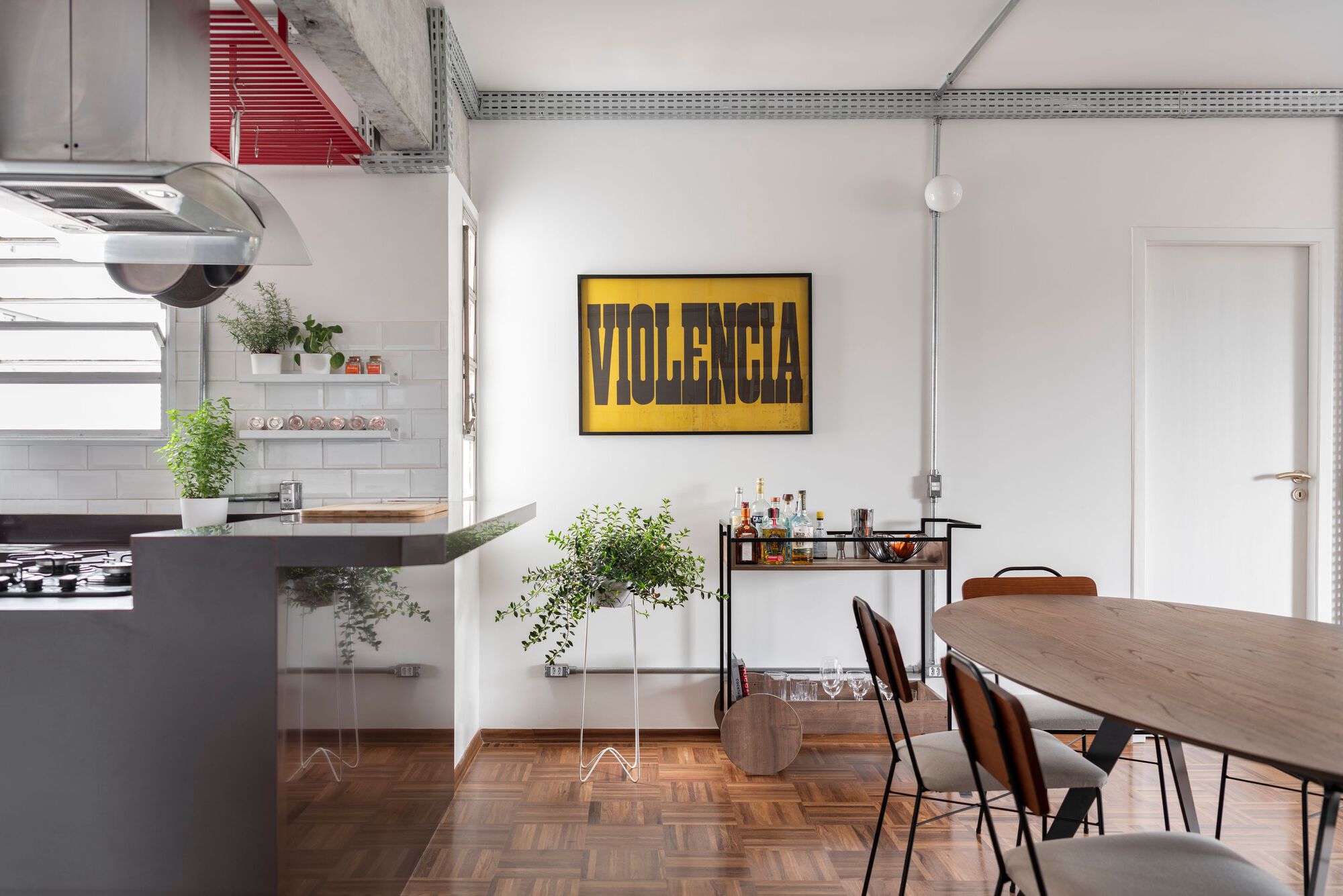 Dining area with graphic artwork and glimpse of white-tiled kitchen beyond