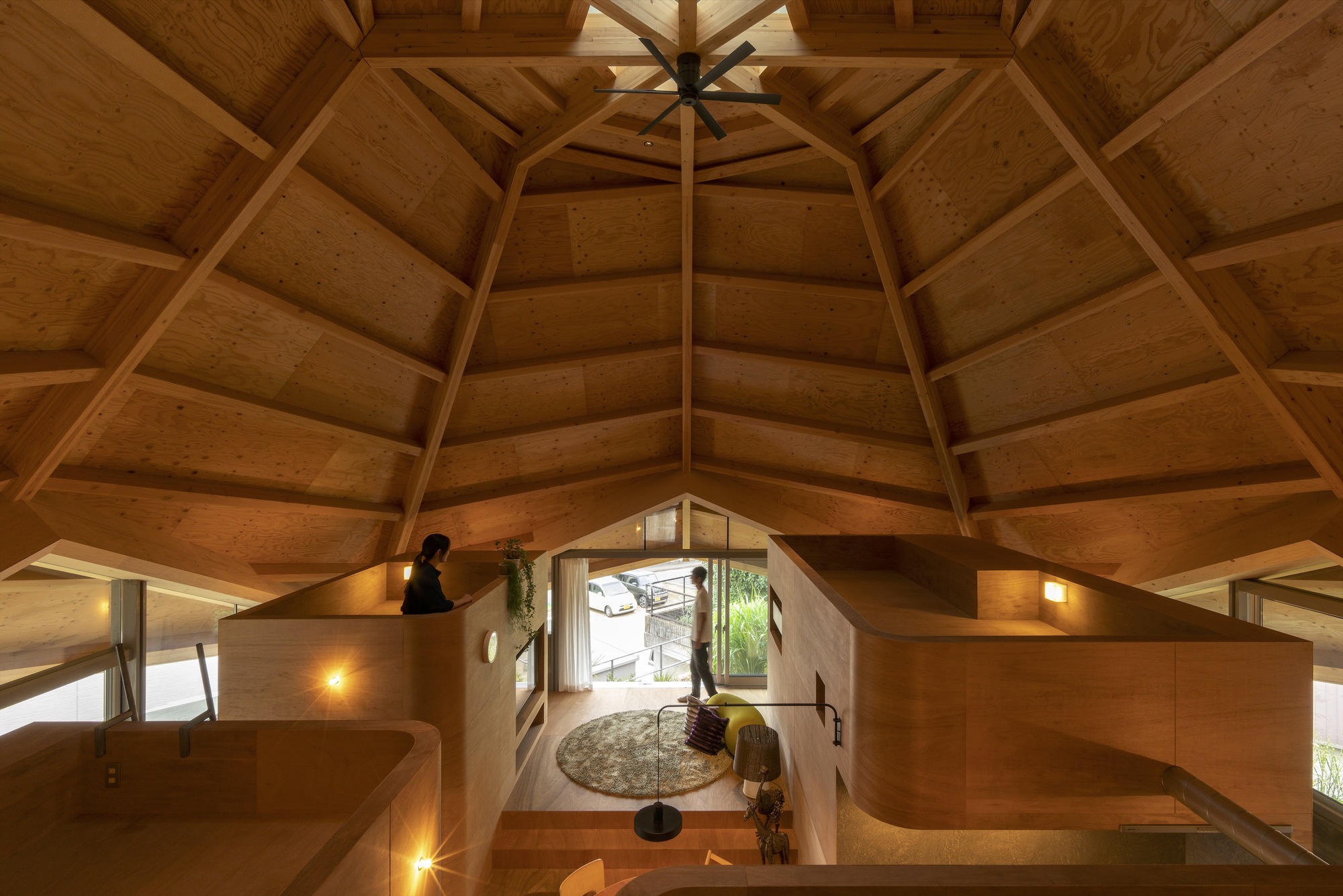 Overhead view from the loft showing the polygonal timber ceiling and plywood partitions enclosing the living space below