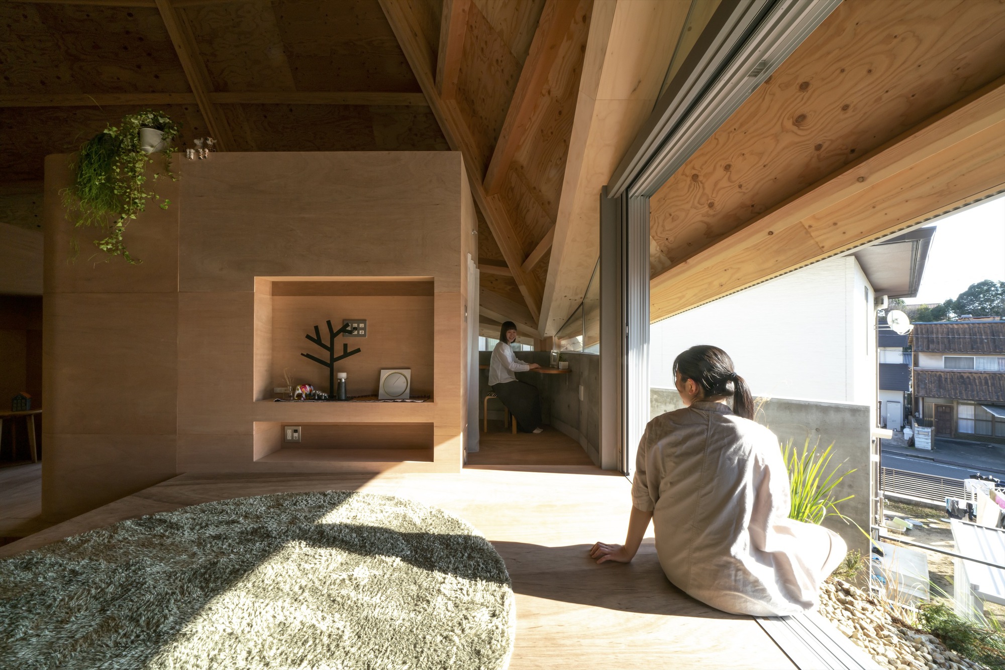 Person seated in an alcove opening to a gravel courtyard with afternoon sunlight streaming inside