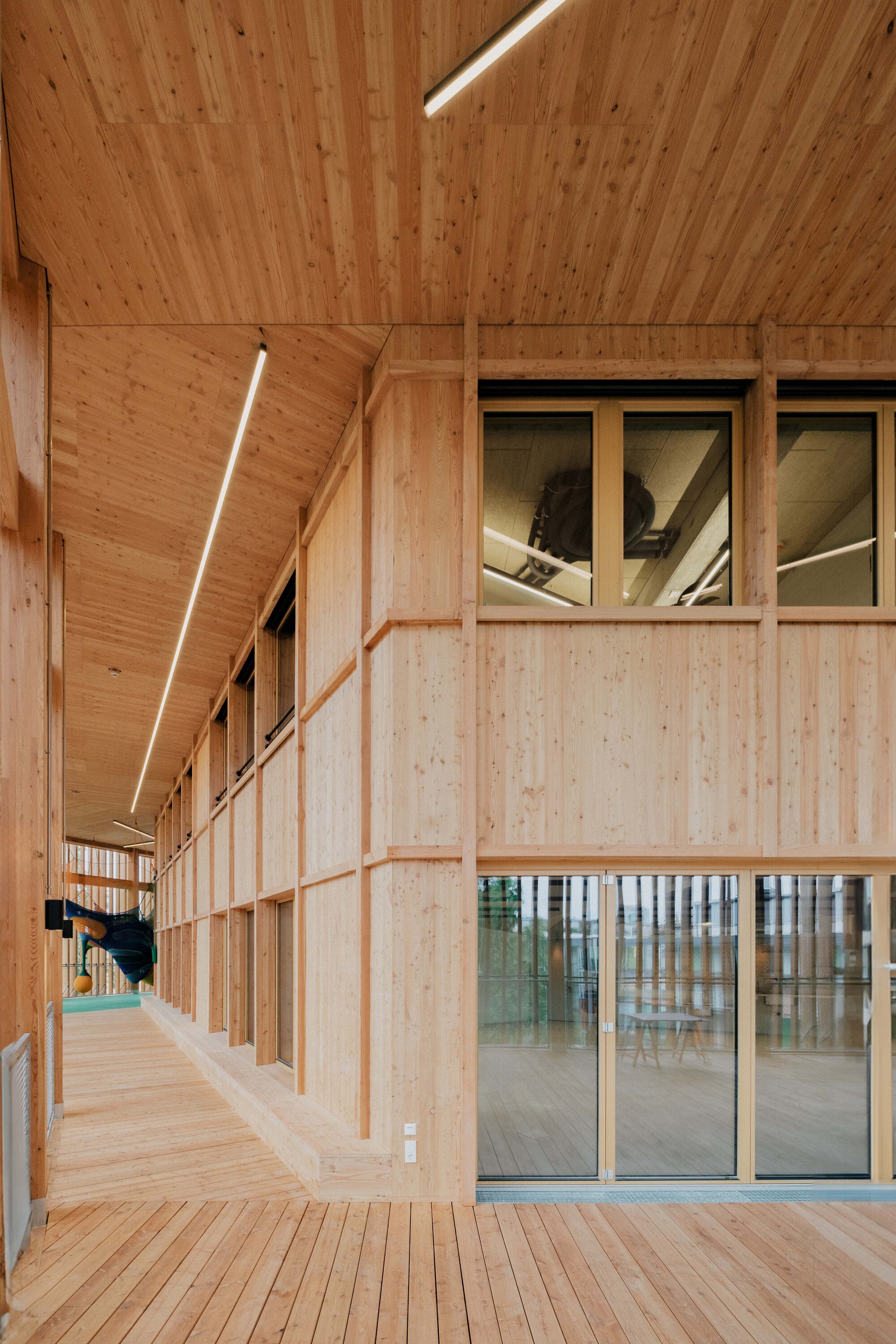 Interior corridor with cross-laminated timber walls, ceiling panels and linear strip lighting