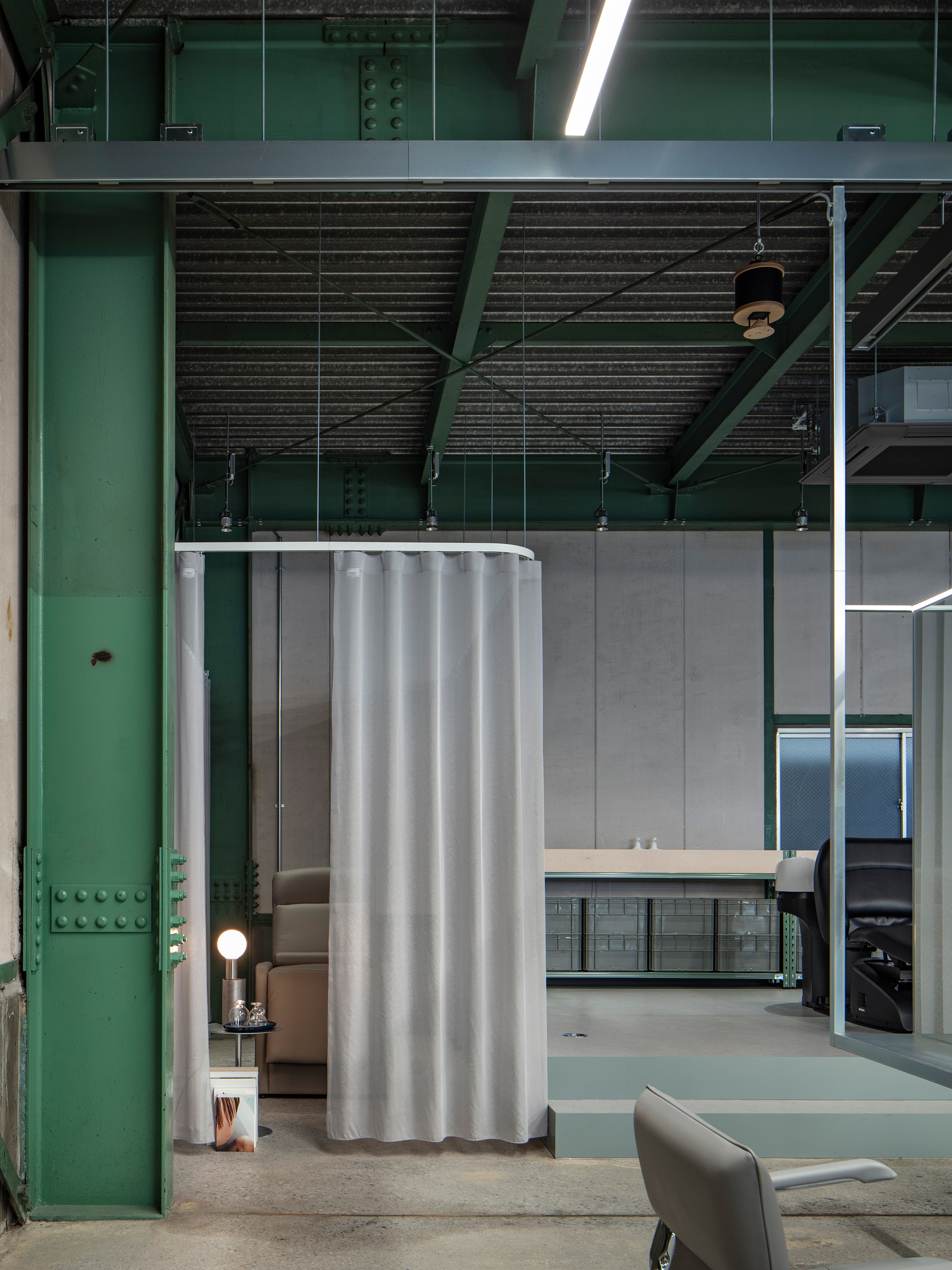 Hair washing station with curtain partition suspended from ceiling beside a green structural column