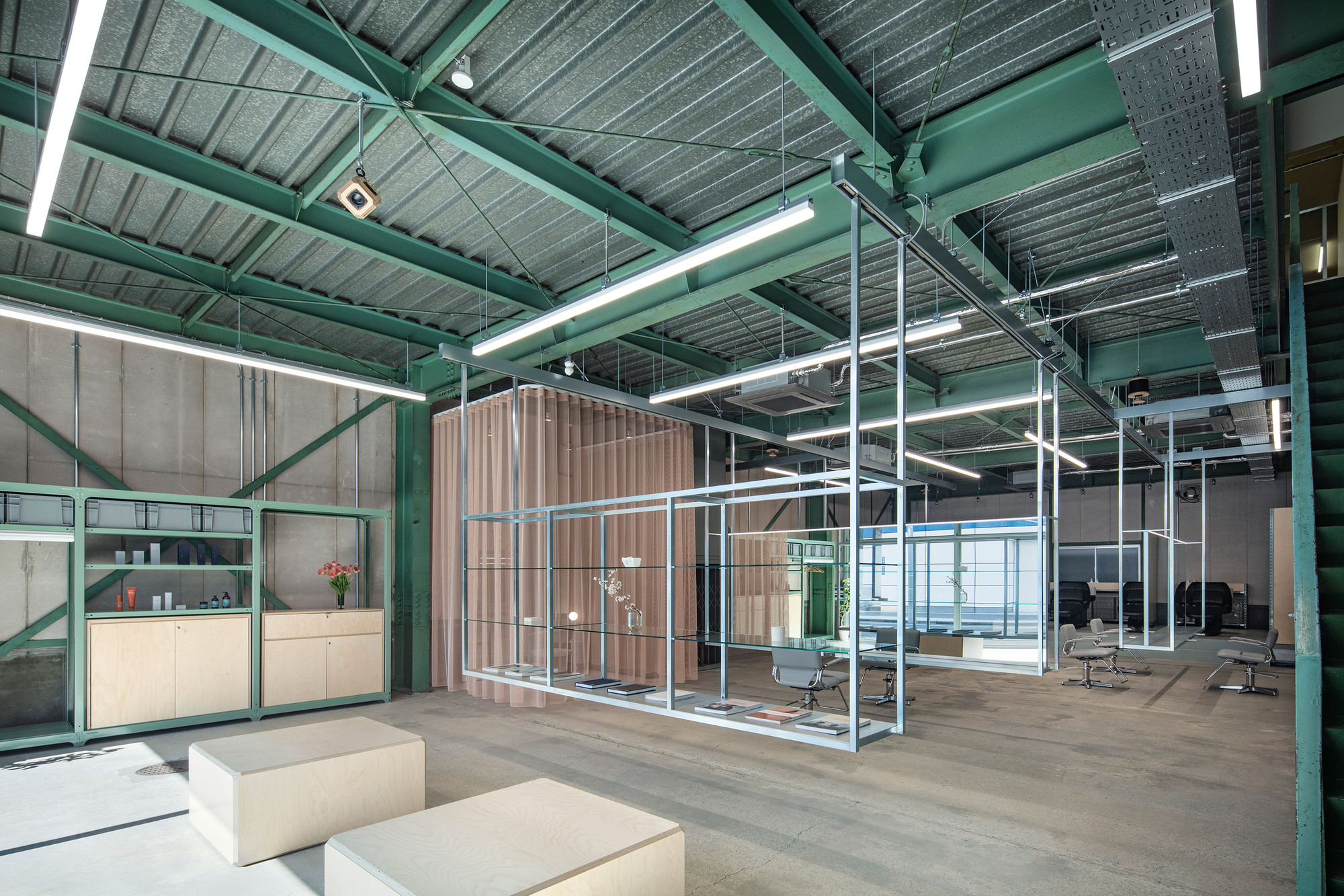 Open office interior with exposed green steel beams, white metal frame partitions and corrugated wood enclosure