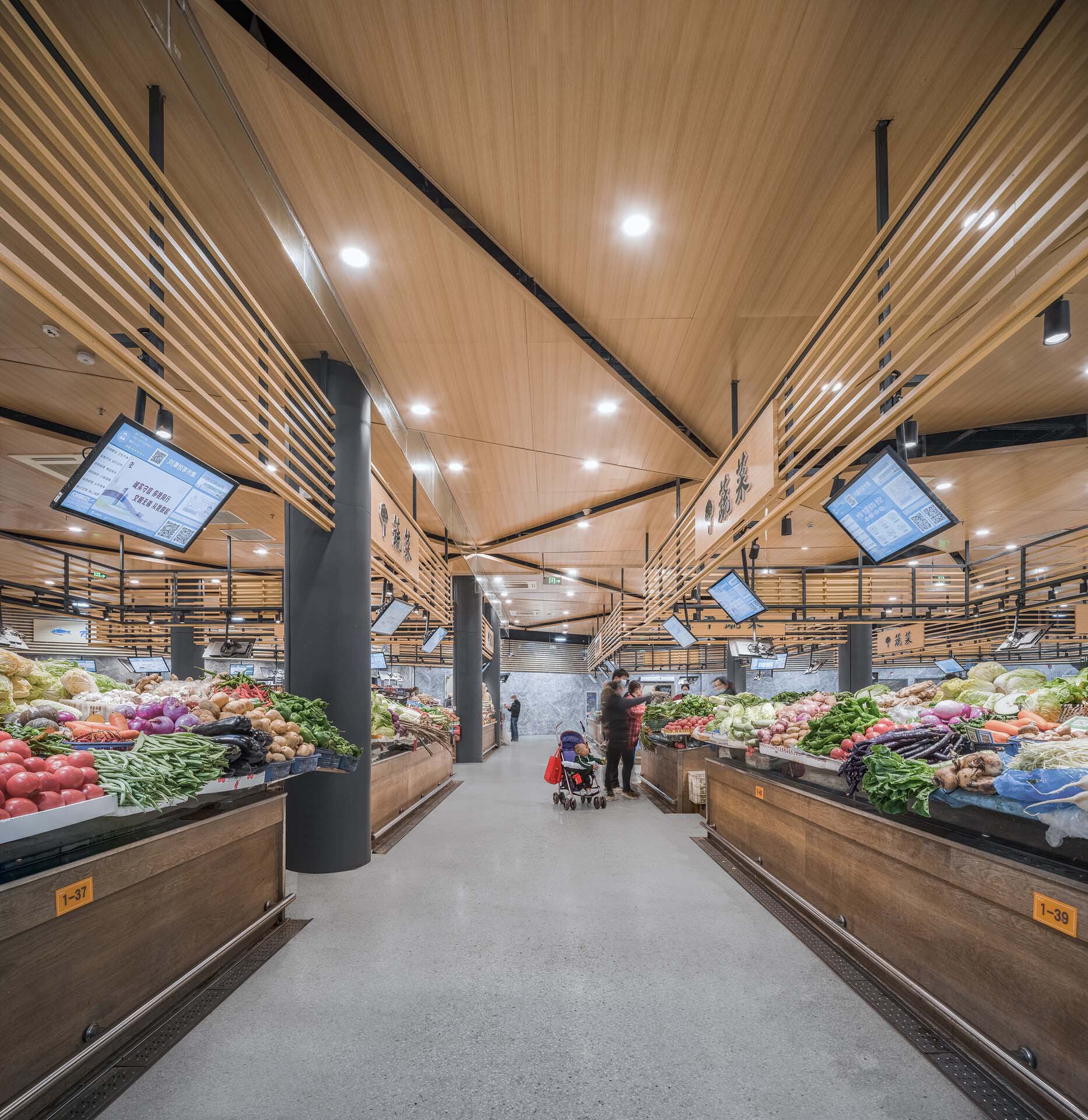 Central aisle with timber ceiling panels, suspended screens and vegetable displays flanking both sides