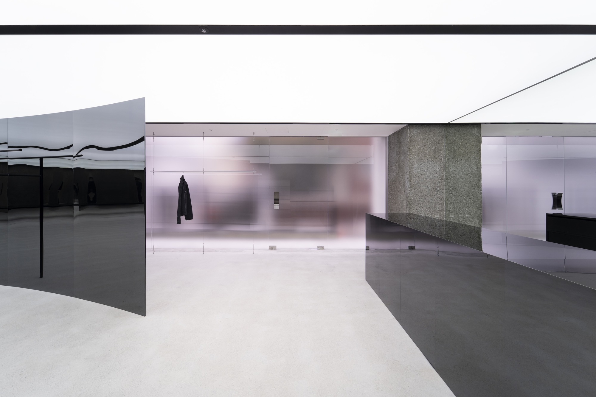 Translucent glass wall and dark metal display surfaces beneath an angular white ceiling plane